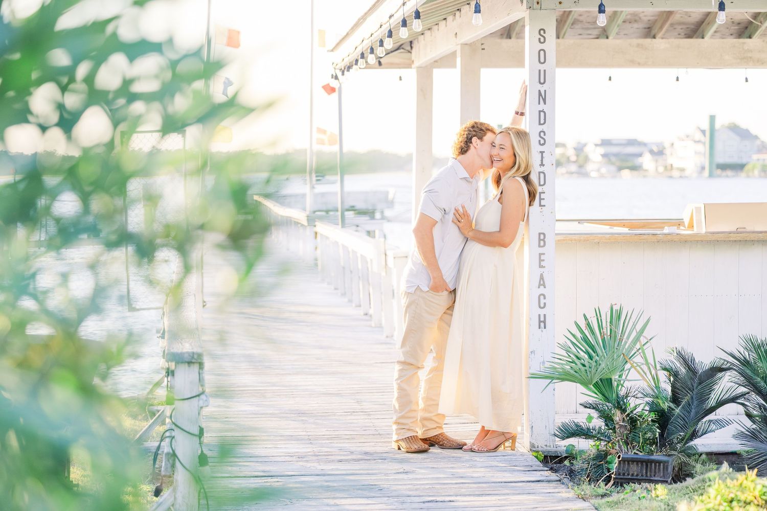 A romantic moment captured on a waterfront dock with soft bokeh effects.