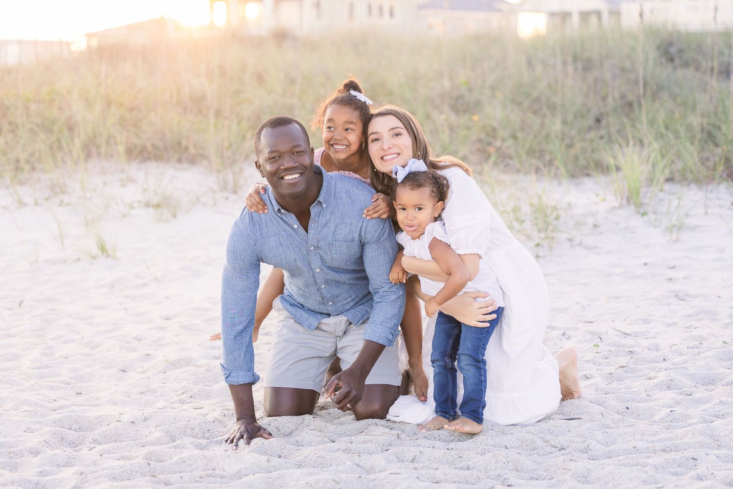 Family enjoying a relaxed photo session on coastal dunes at sunset.