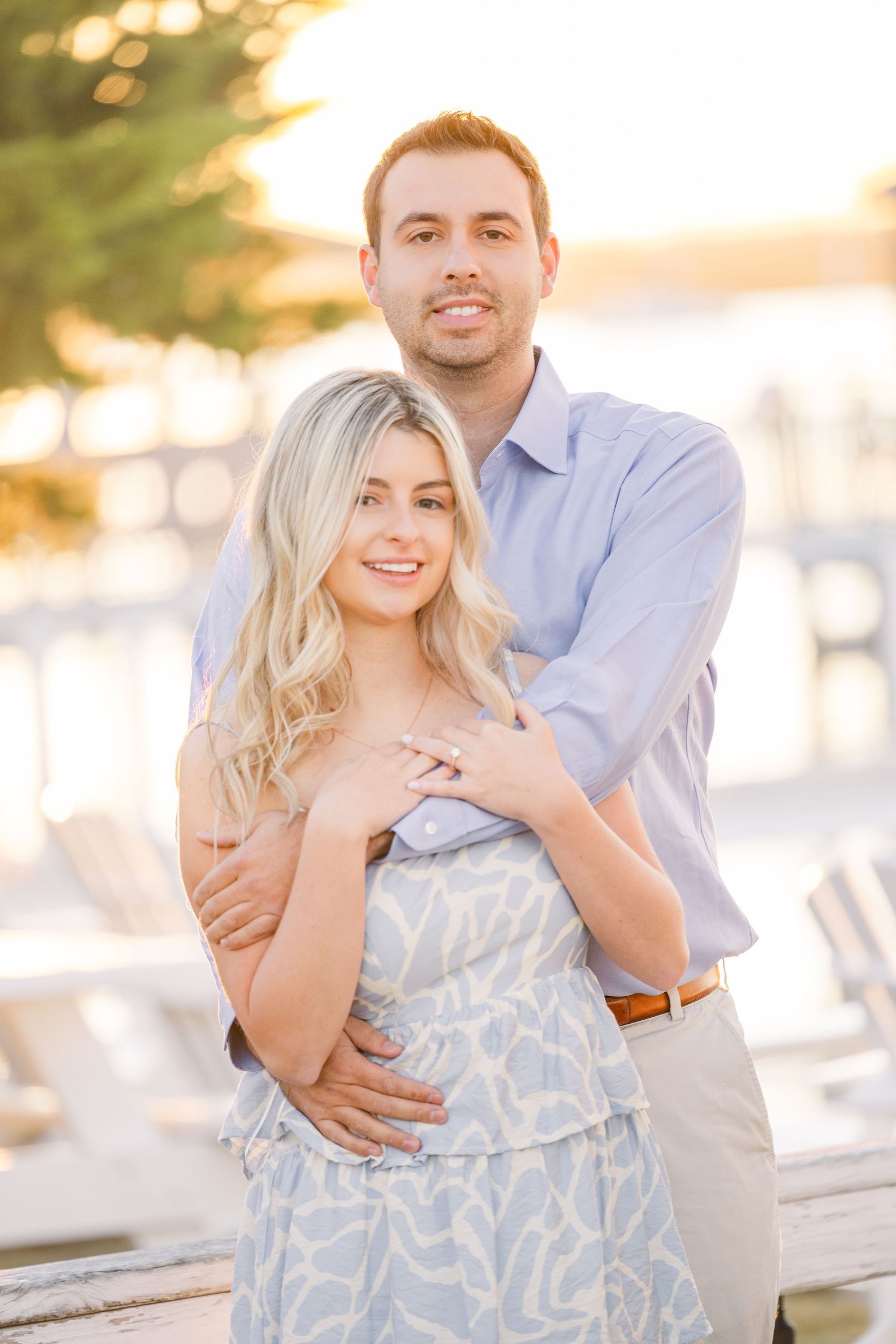Tender embrace on coastal boardwalk with soft sunset lighting and water views.