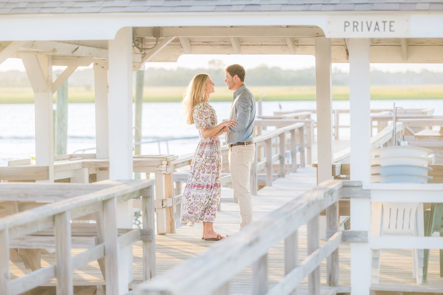 A couple shares an intimate moment on a private dock with waterfront views.