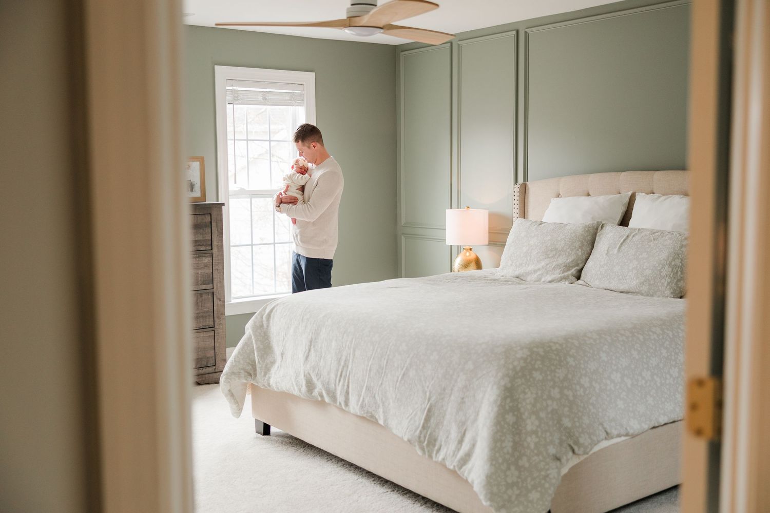 Bright bedroom interior with white bedding and natural light streaming through windows.