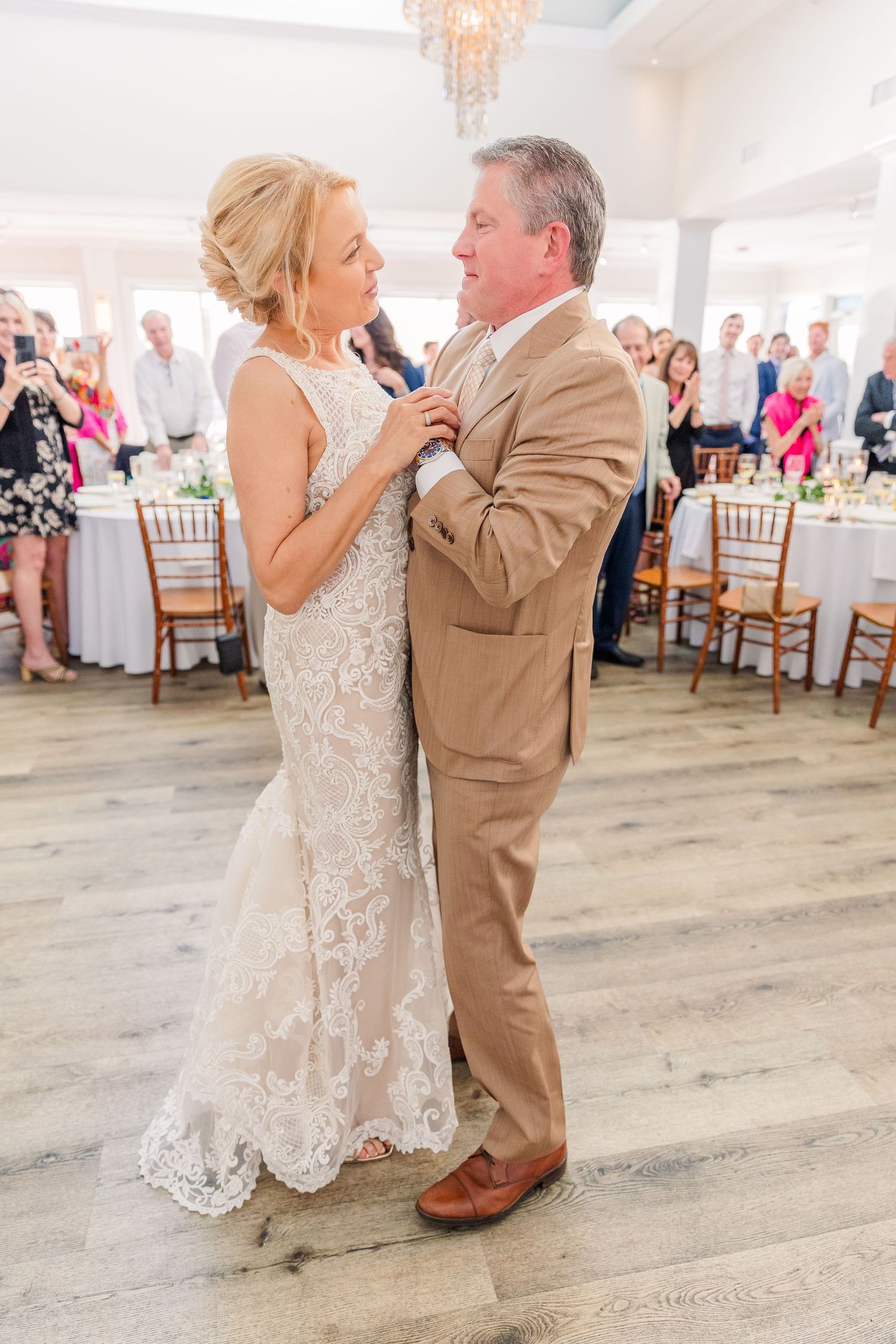 Couple sharing a romantic dance moment on a light wood floor at their wedding reception.