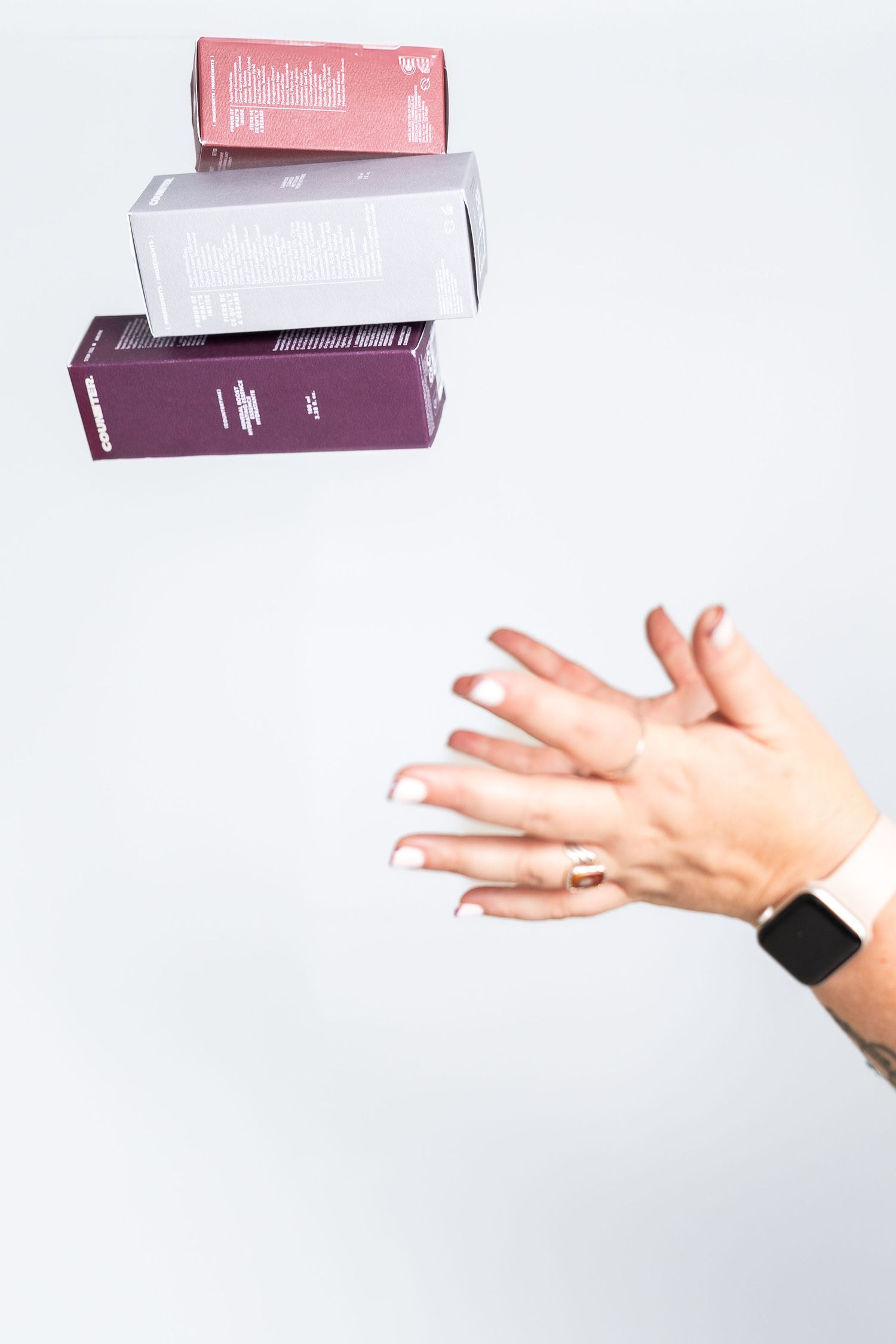 Hand catching falling purple product box in motion against white background.