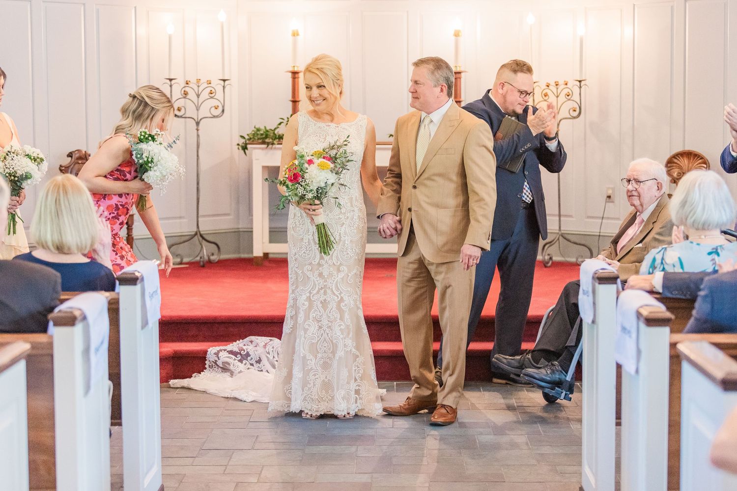 Wedding ceremony in progress with church pews and candelabras visible in background.