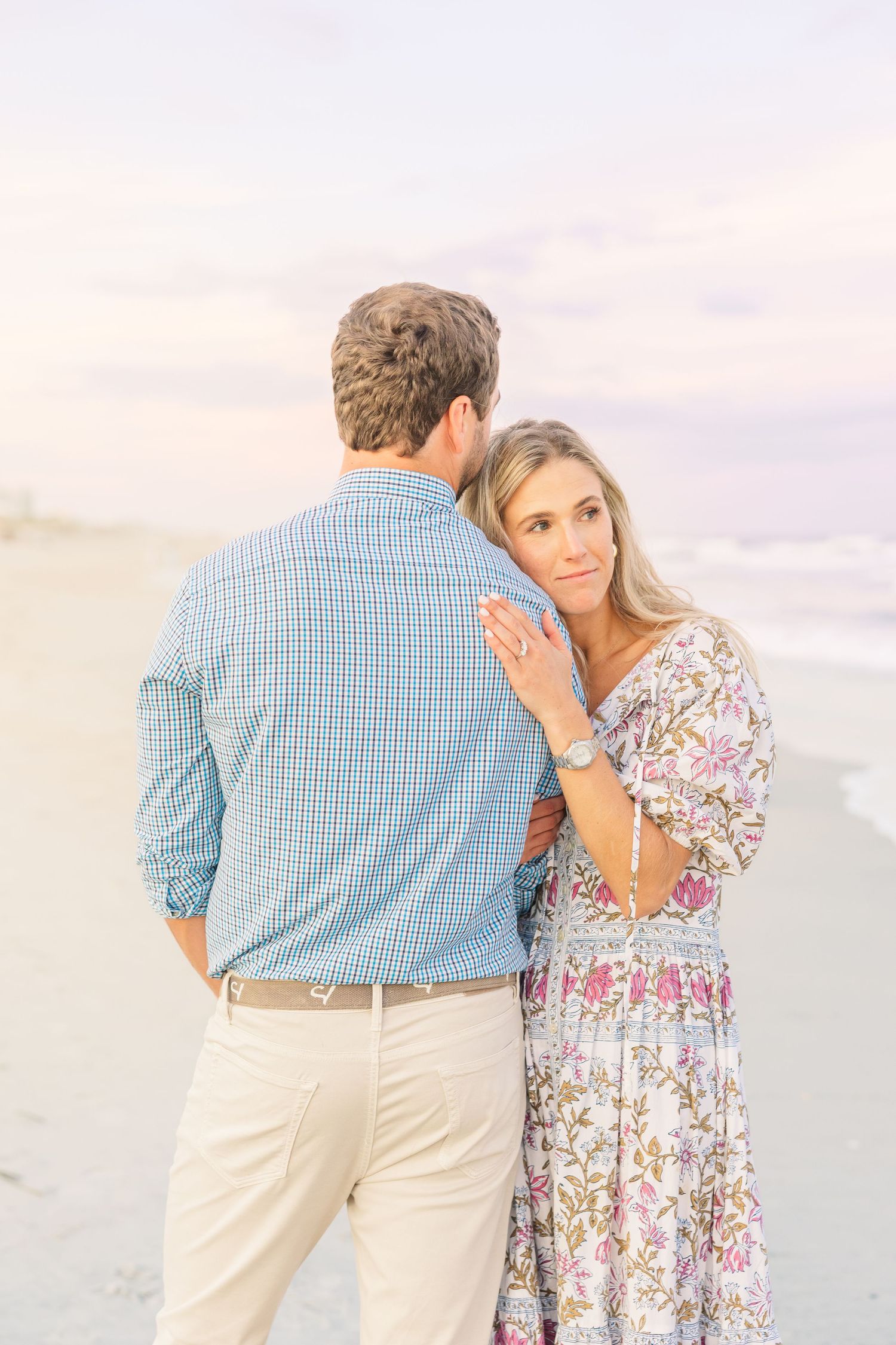 Romantic beachside moment between couple with gentle ocean waves in background.