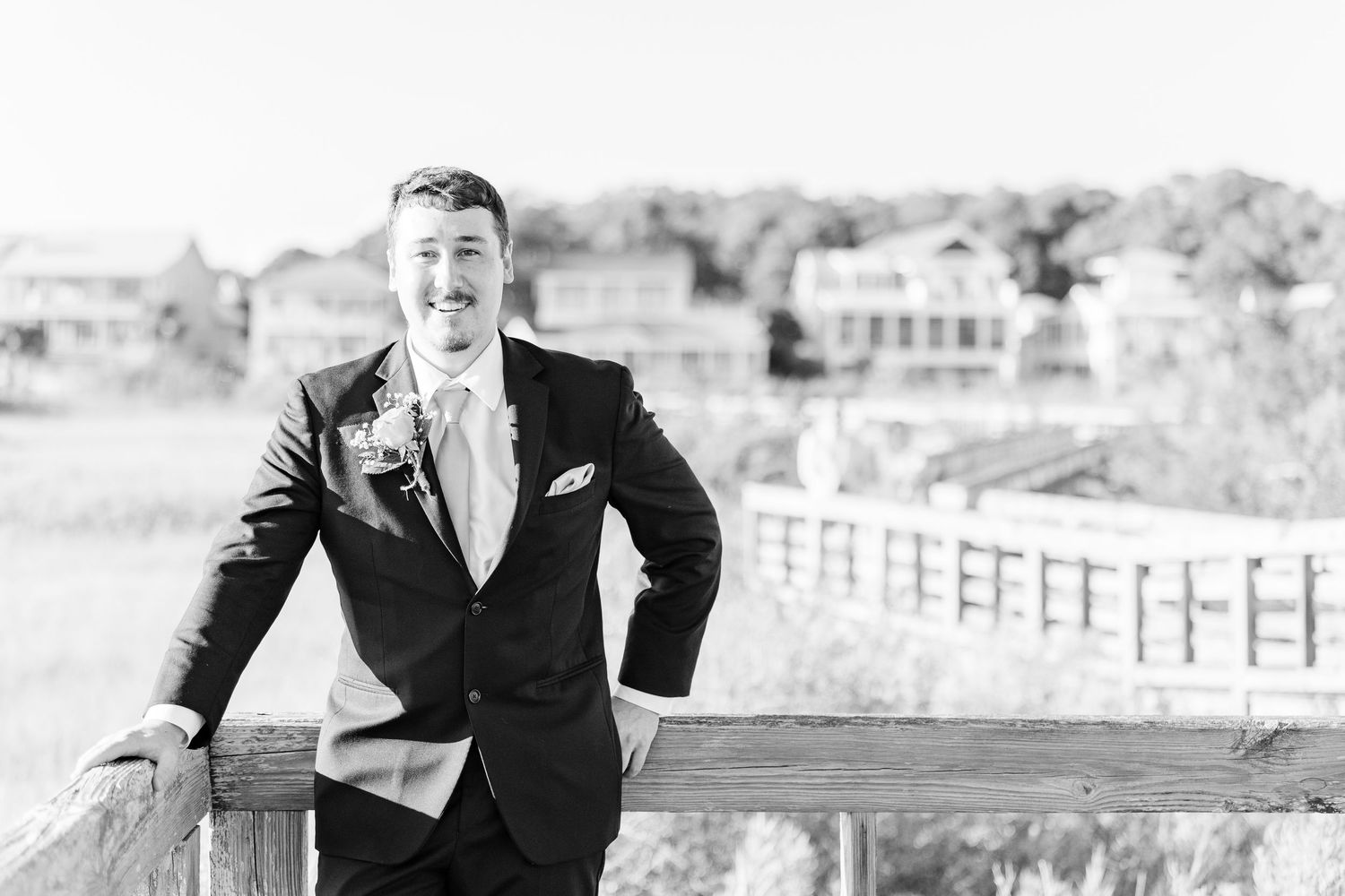 A couple shares a joyful moment together on a wooden boardwalk by the beach southport elopement wedding bride groom light and airy classic
