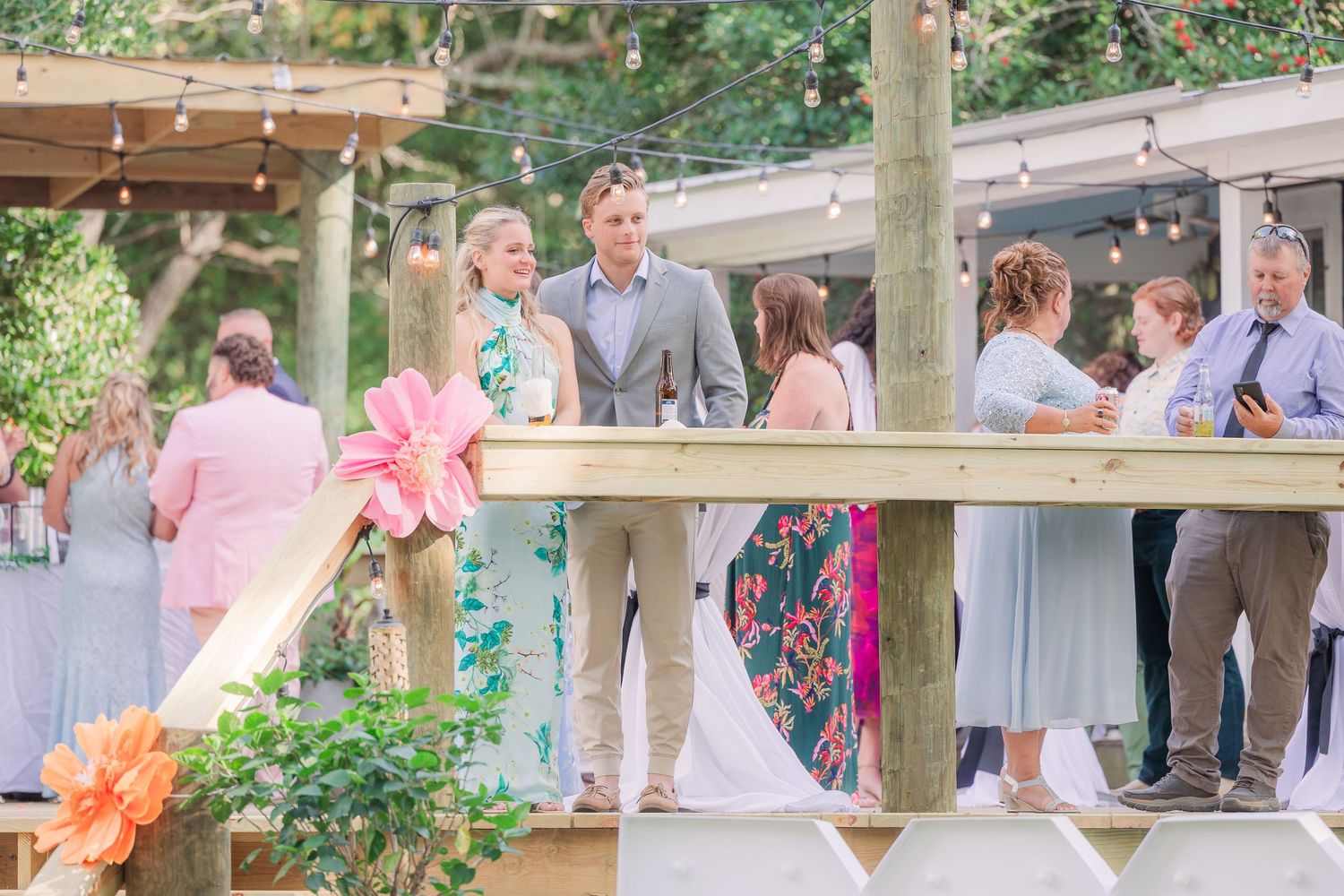 Guests gather on a wooden deck during an outdoor wedding groom bride wilmington photographer light and airy classic Wrightsville Beach
