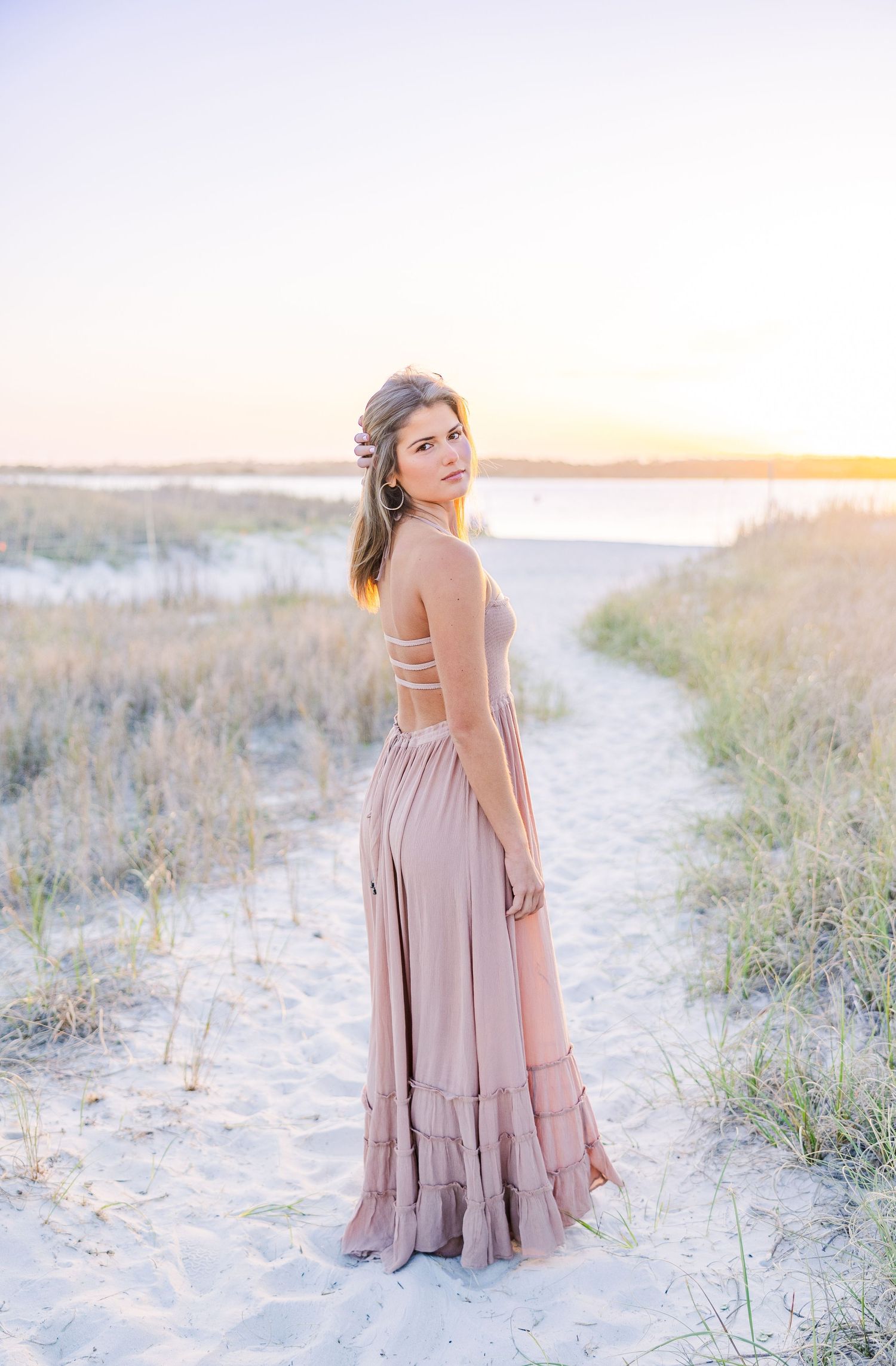 Beachy sunset photoshoot featuring a mauve dress against coastal dunes and natural vegetation.