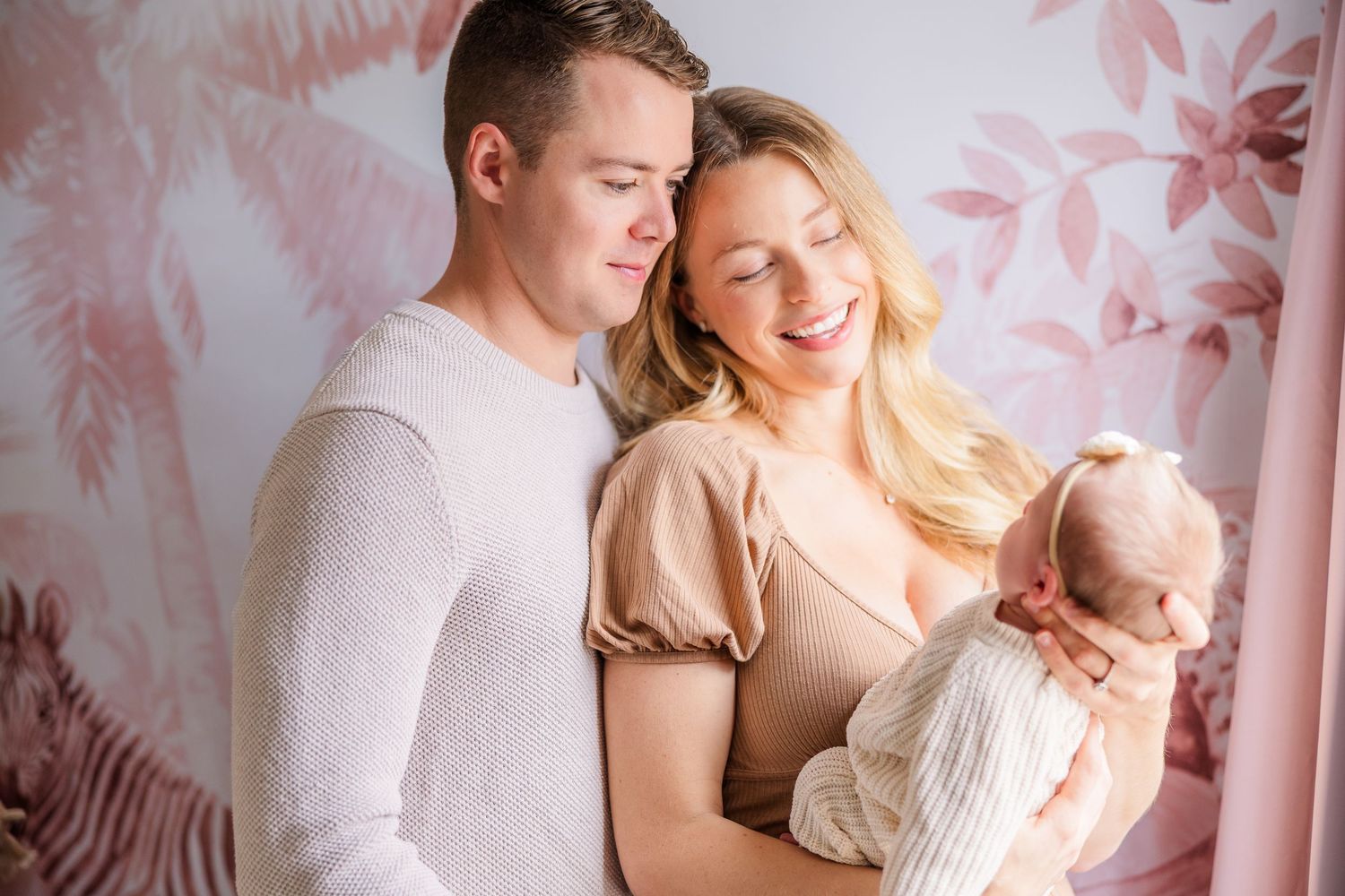 Sweet family photoshoot featuring soft pink tones and natural window lighting.