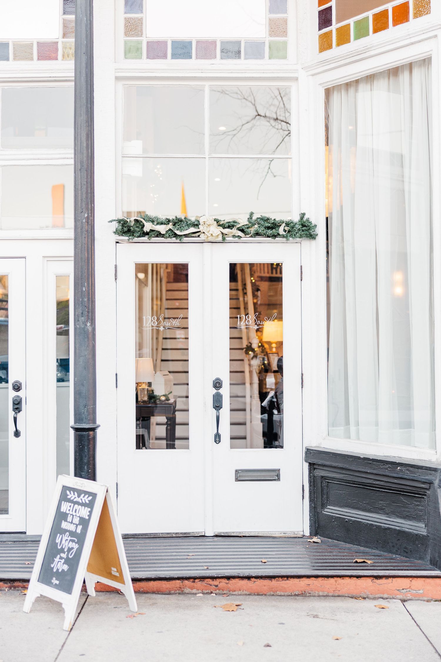 Modern white building exterior with large windows and chalkboard signs.