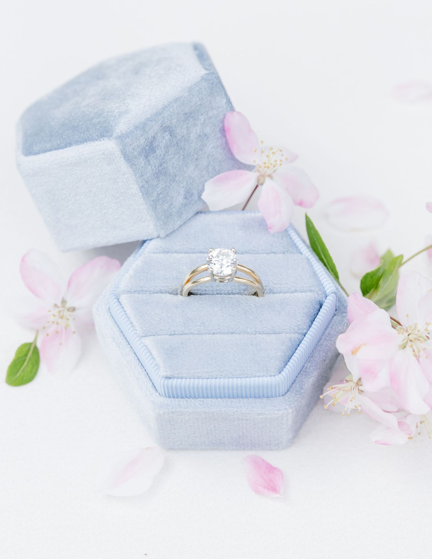 Elegant diamond engagement ring in a powder blue velvet ring box with delicate pink flowers.