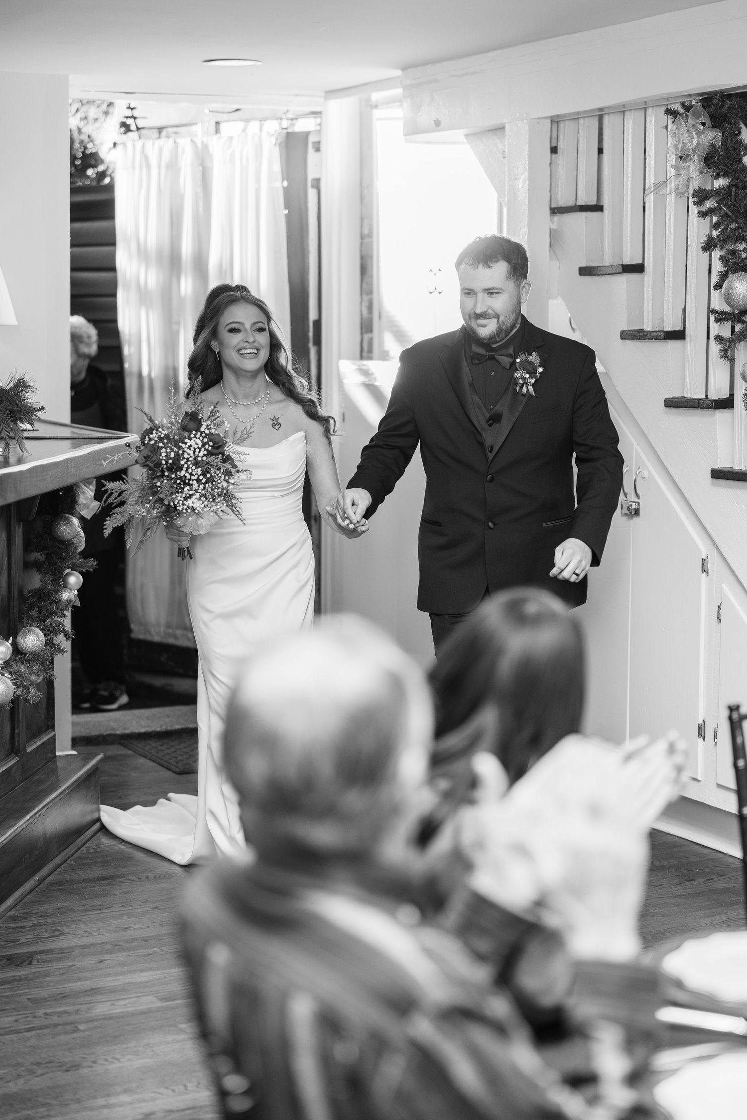 Wedding couple walking through an indoor venue holding hands and smiling.