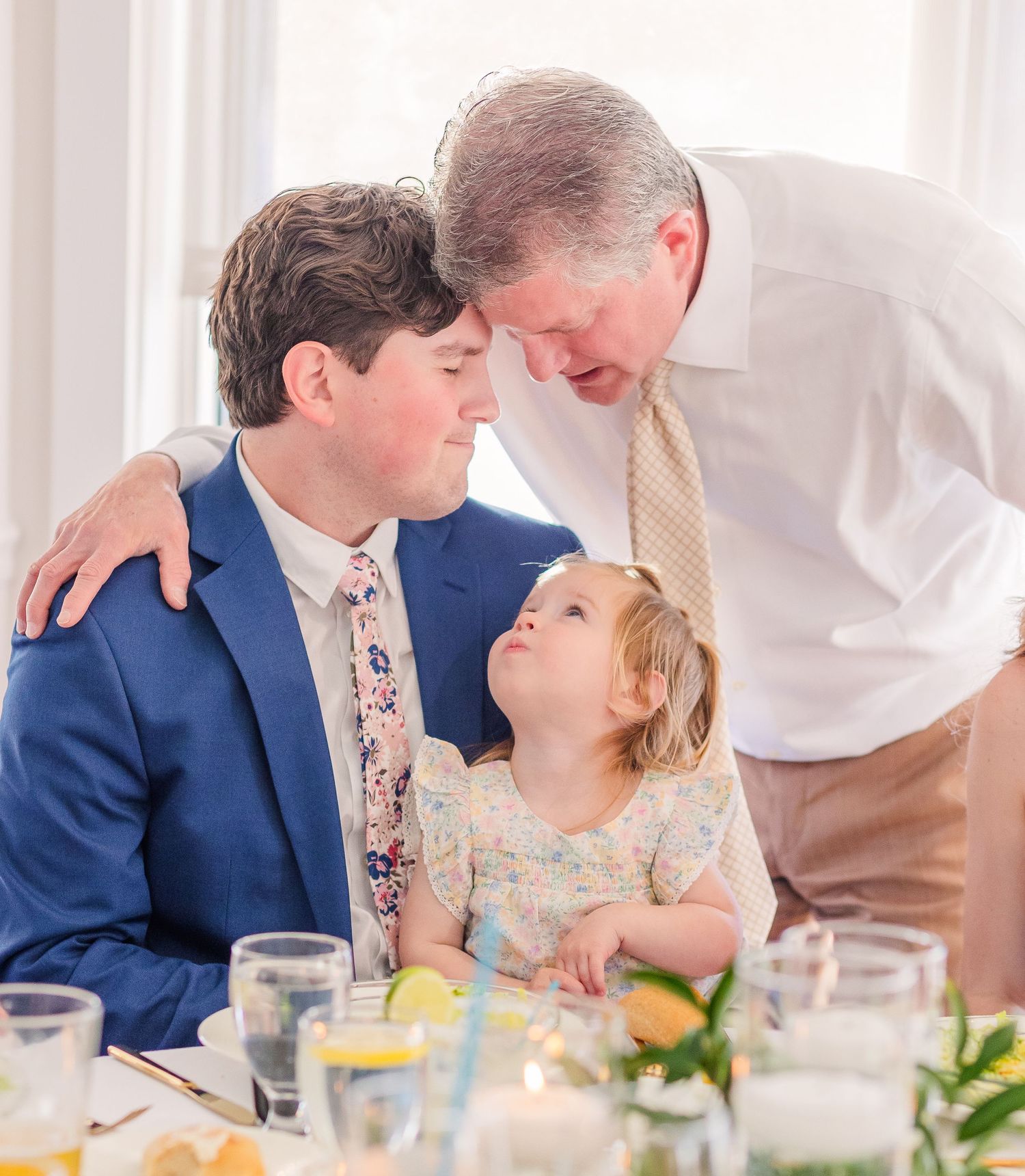 Wedding reception dining scene with guests in formal attire sharing intimate moments.