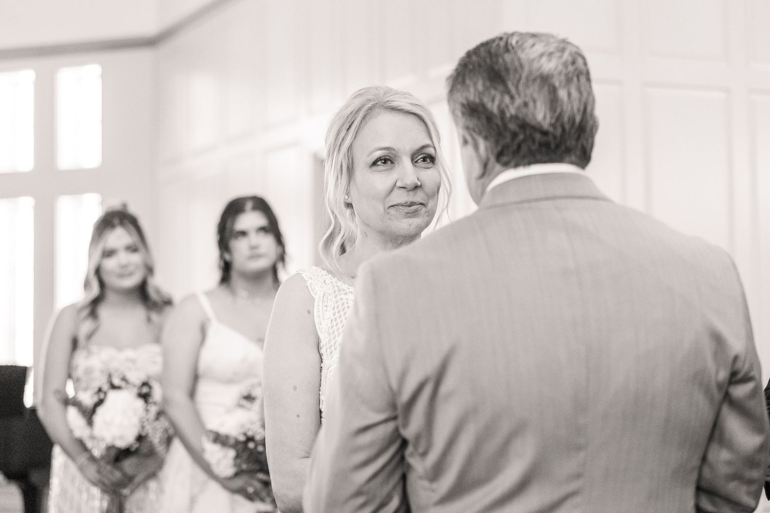 Intimate wedding ceremony moment in bright white church with elegant decor.