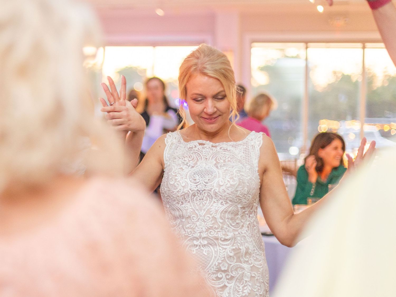 A person in a sparkly white dress dances joyfully at a wedding reception.