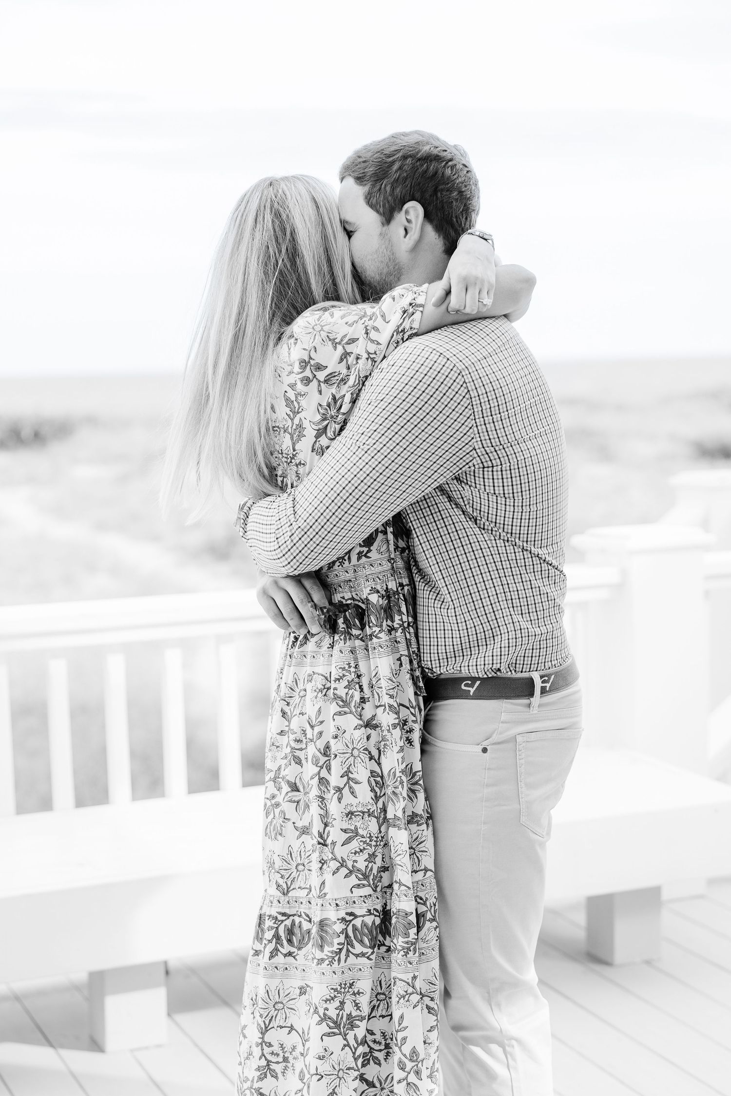 Black and white image of a romantic embrace on a coastal porch.