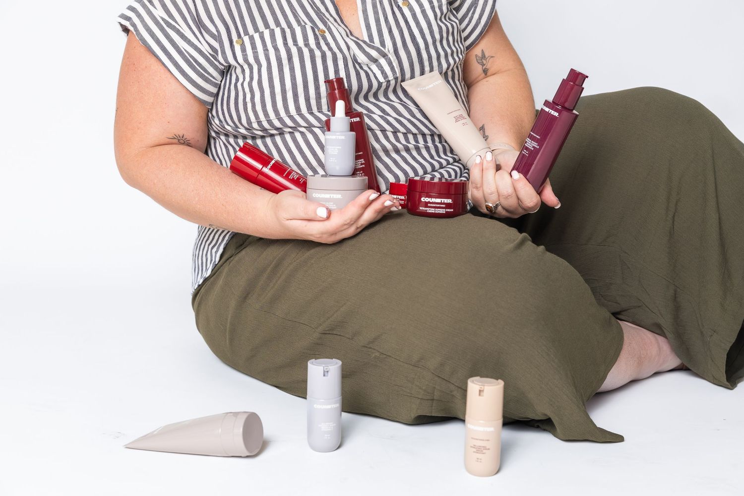 Person arranging skincare products while sitting on floor.
