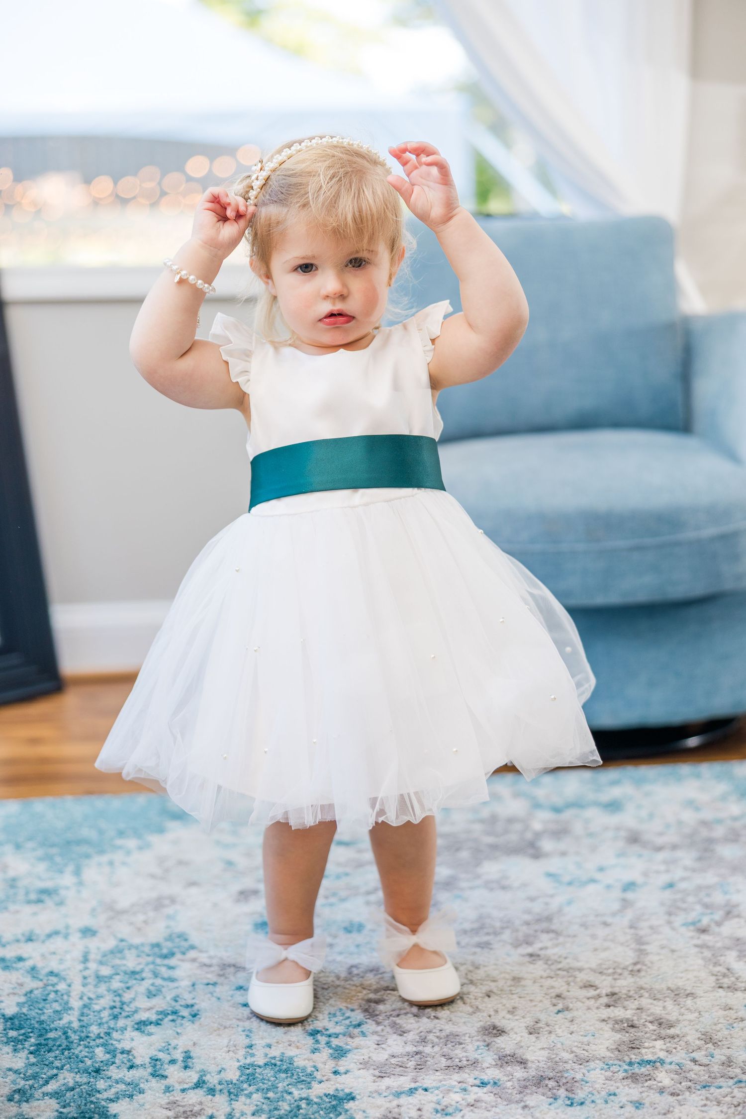 A small child in a white tulle dress twirls on a patterned blue and white rug wedding groom bride lake Gaston photographer light airy
