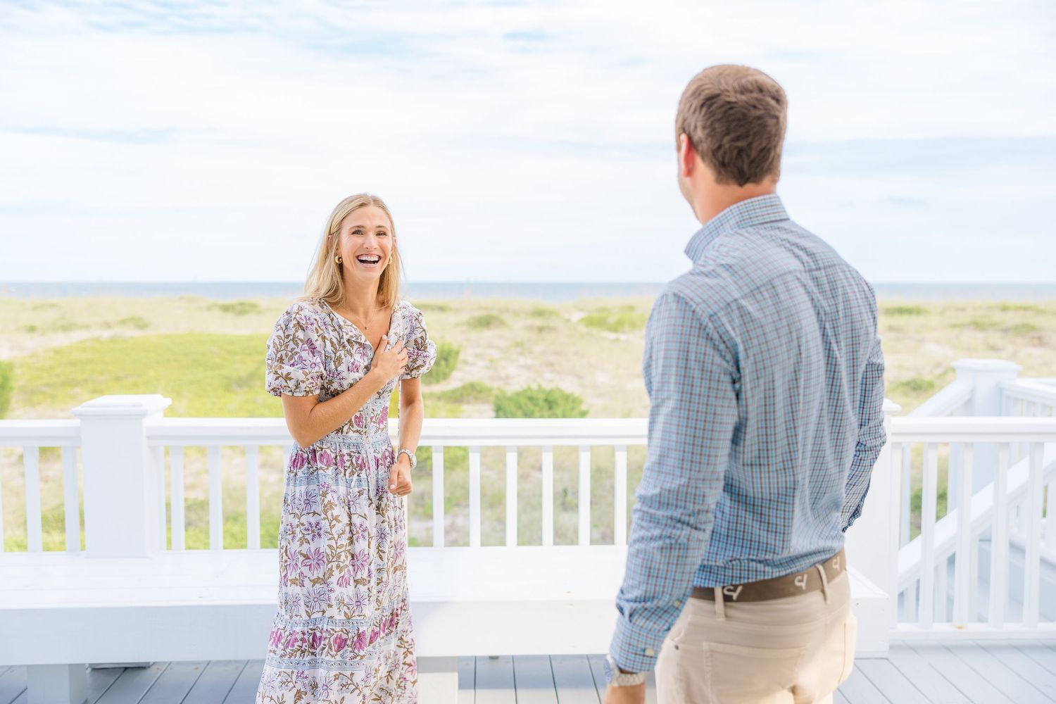 Couple sharing an excited moment on an oceanfront deck in summer clothing.