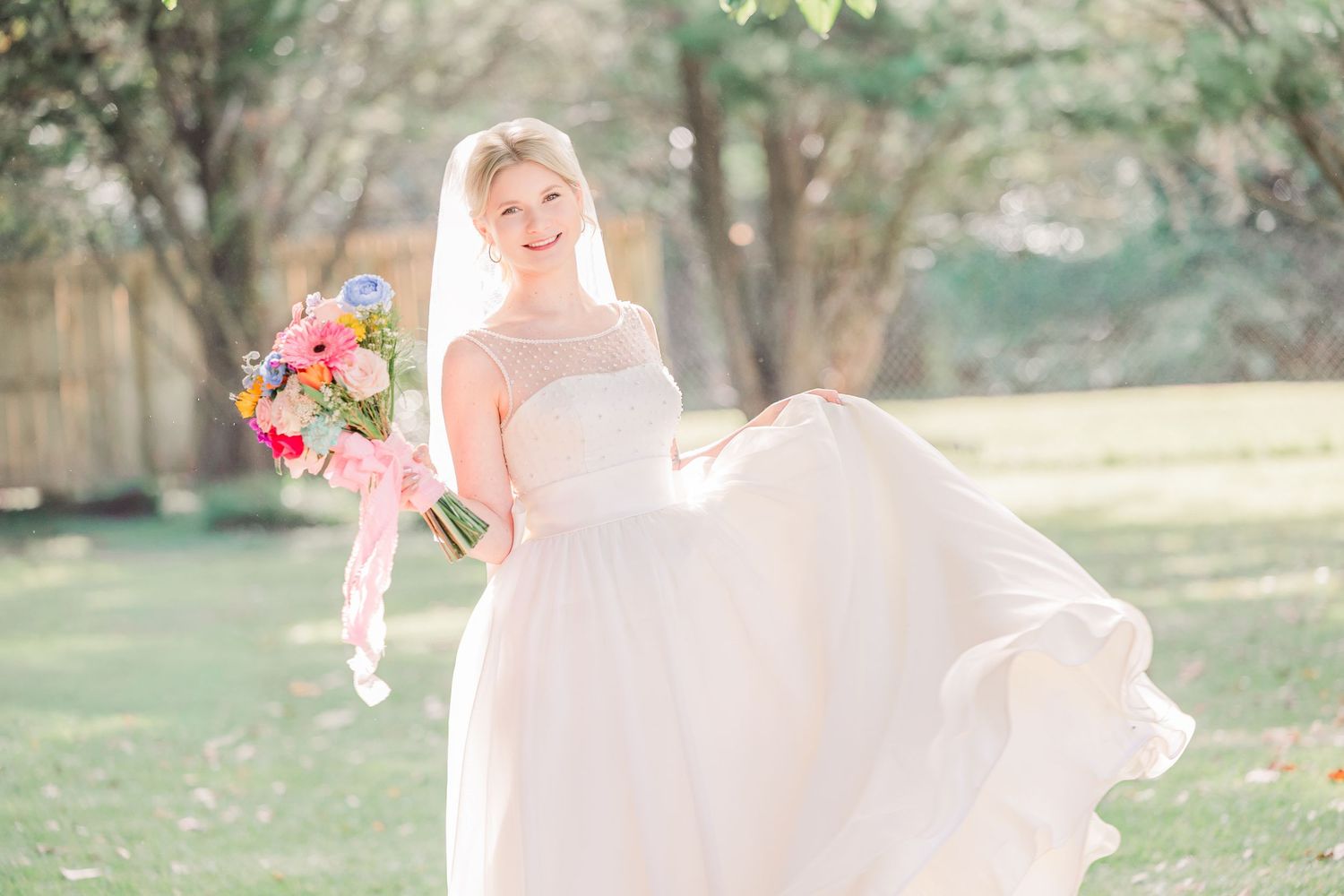 A flowing white wedding dress photographed against a natural garden backdrop.