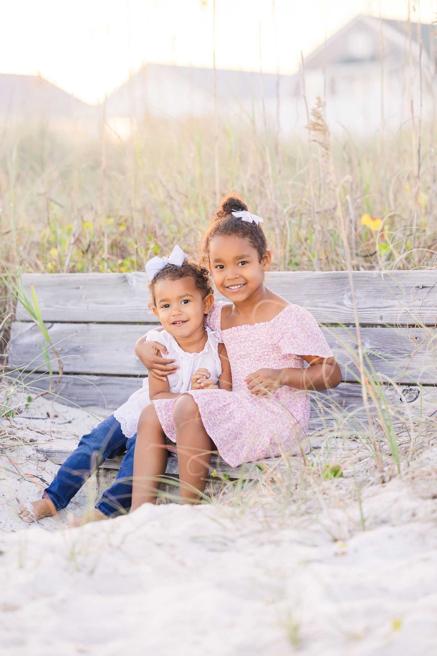 Children playing together in the sand during a beach photo session.