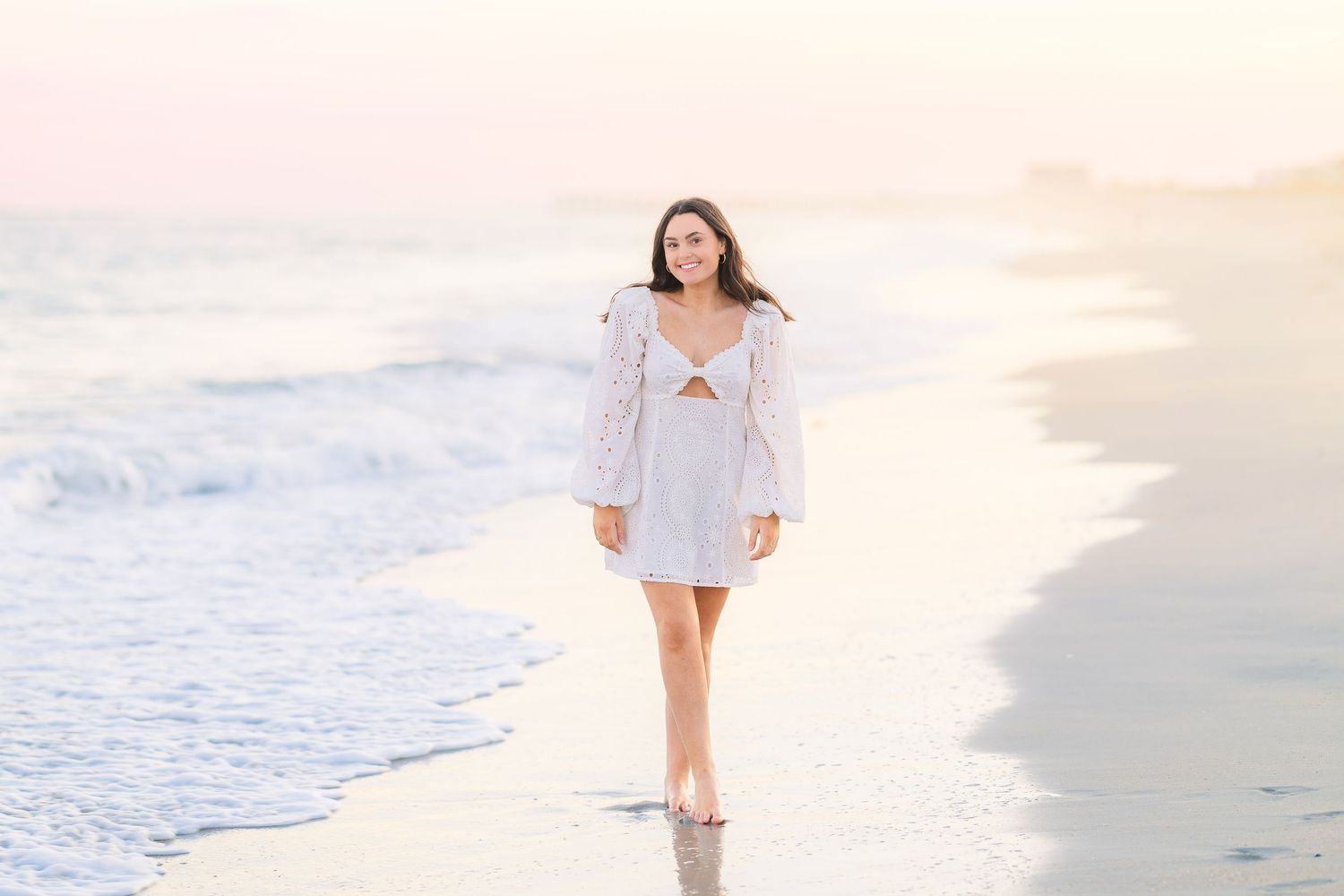Romantic beach walk captured in soft lighting wearing a white summer dress.