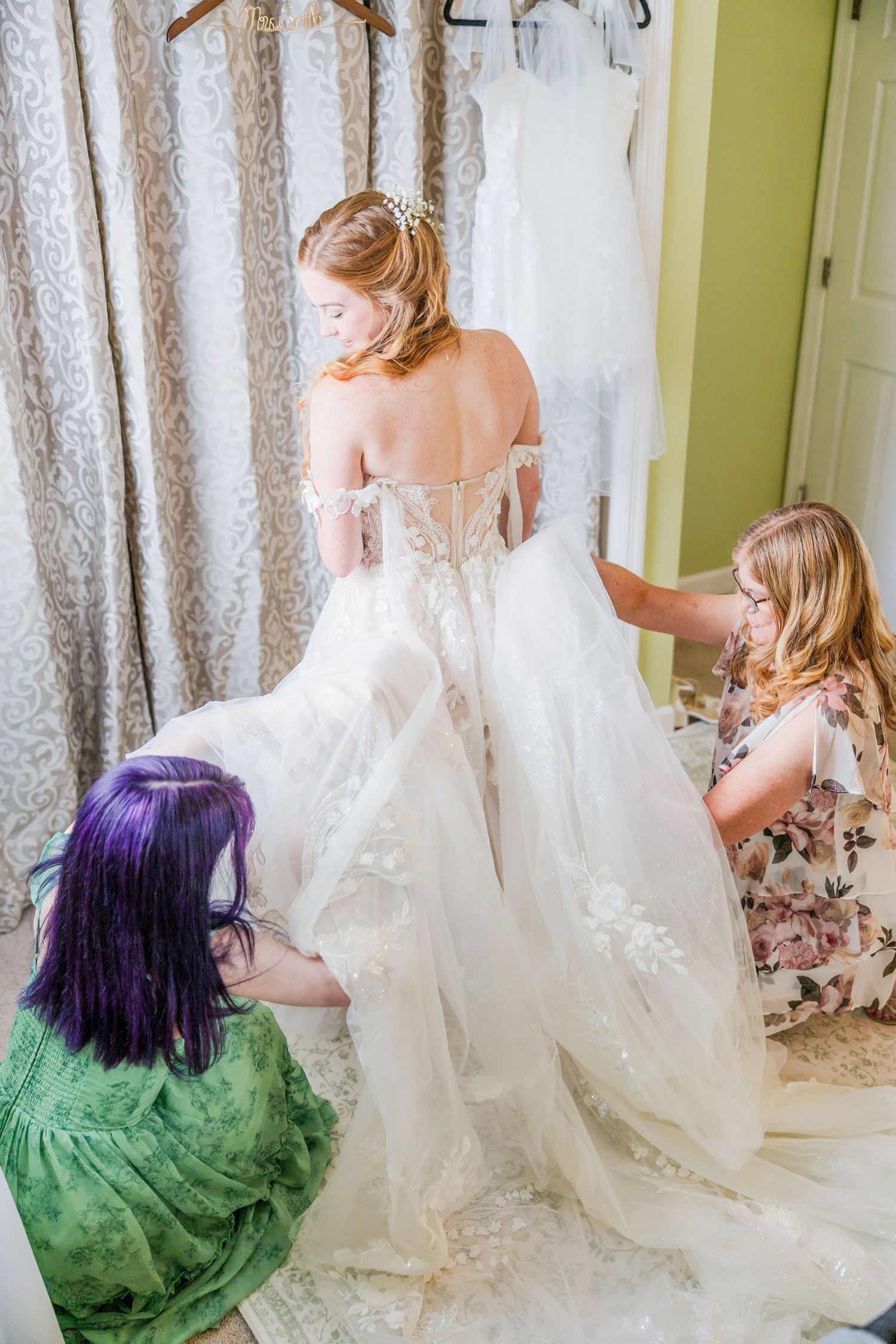 Wedding dress fitting with helpers adjusting the train of an elegant white gown in a backyard wedding in wilmington, nc