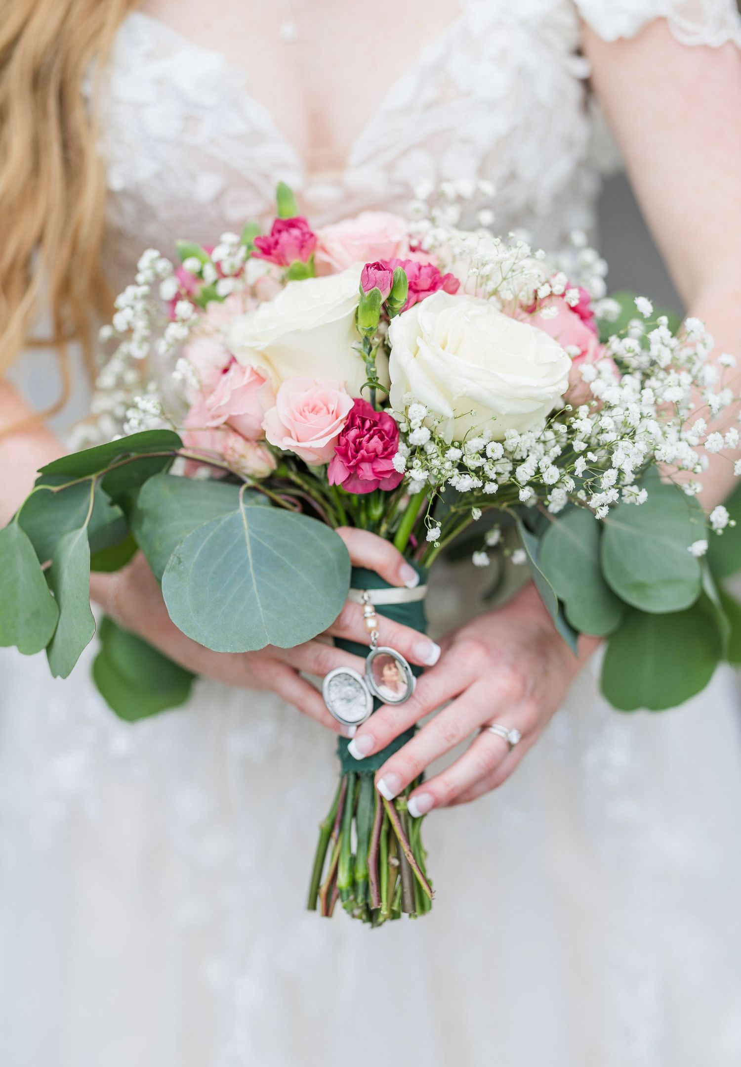 Wedding bouquets with pink roses, white flowers and eucalyptus leaves held by hands in white dresses in wilmington, nc