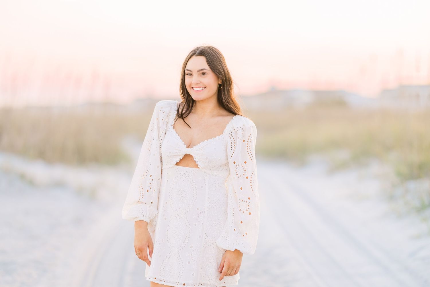 Bright and airy beach portrait in a white lace top against soft natural lighting.