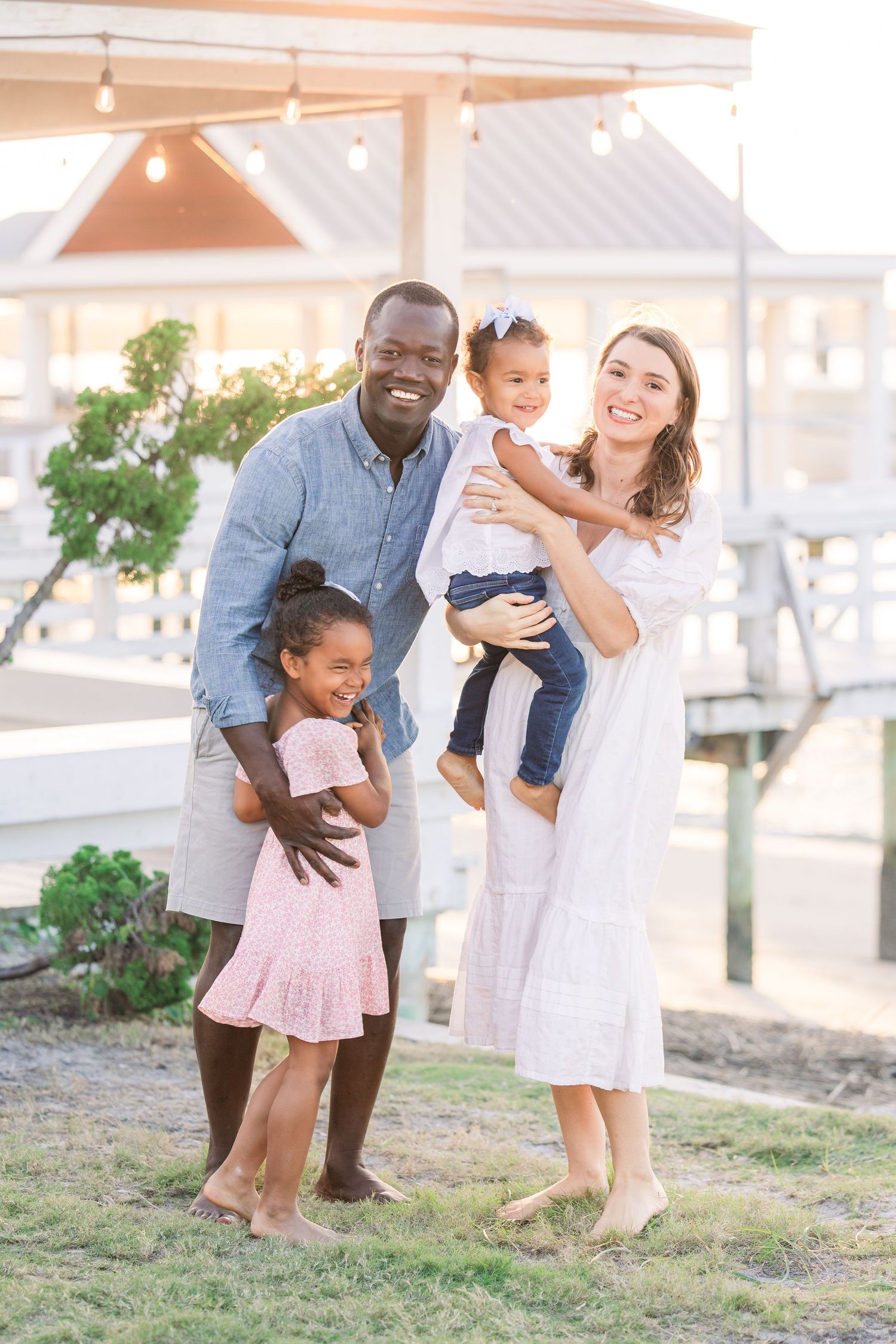 Happy family sharing laughs and embraces in front of a coastal backdrop.