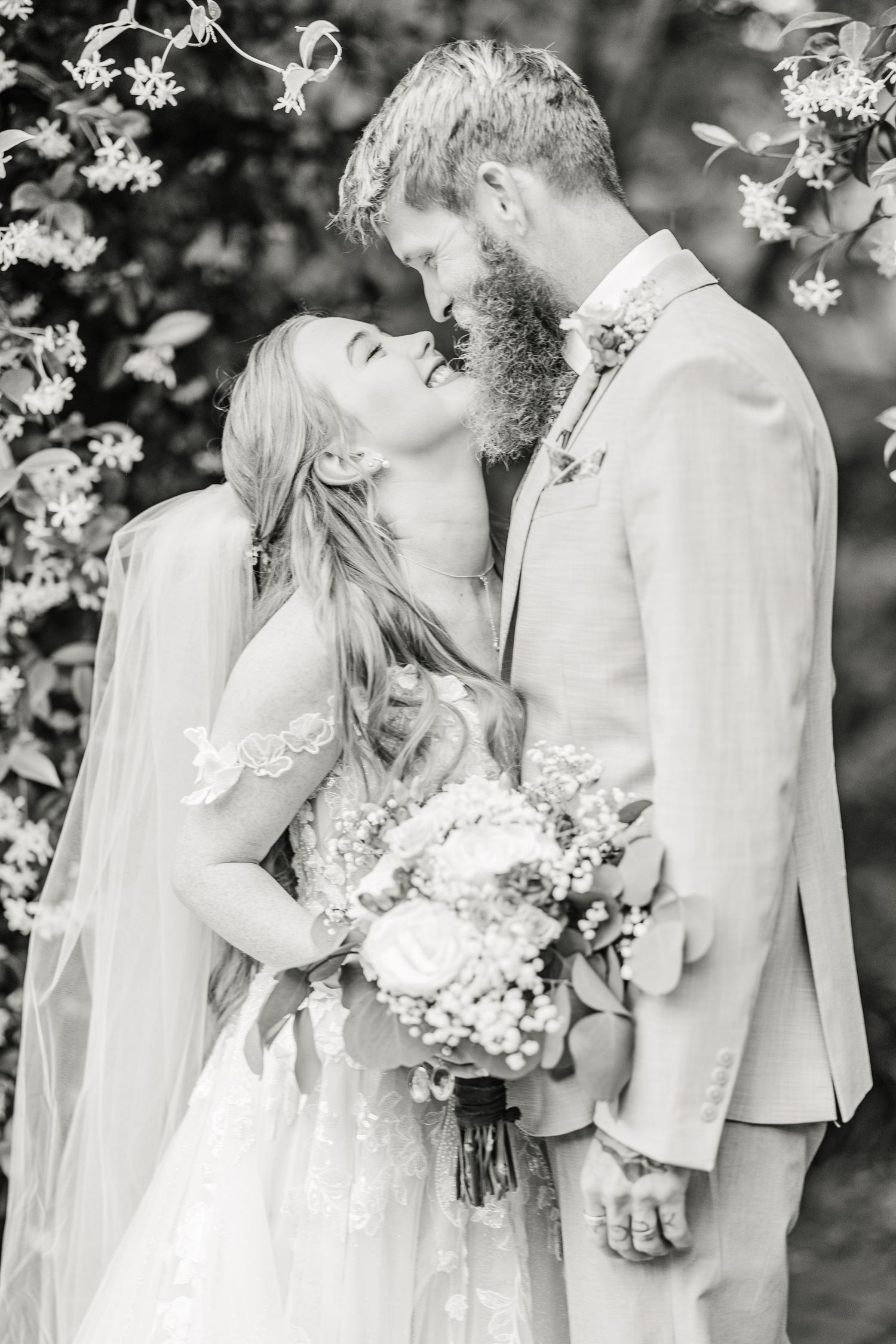 Black and white wedding photos capture intimate moments between newlyweds under flowering trees in harborway gardens in Wrightsville Beach