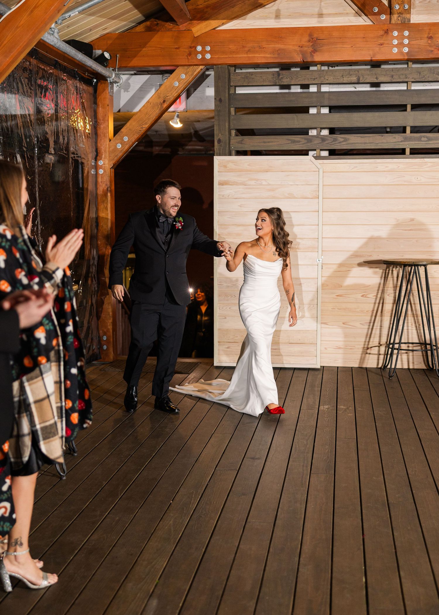 A couple makes their grand entrance at a rustic wedding venue with wooden beams and deck flooring wedding groom bride wilmington North Carol