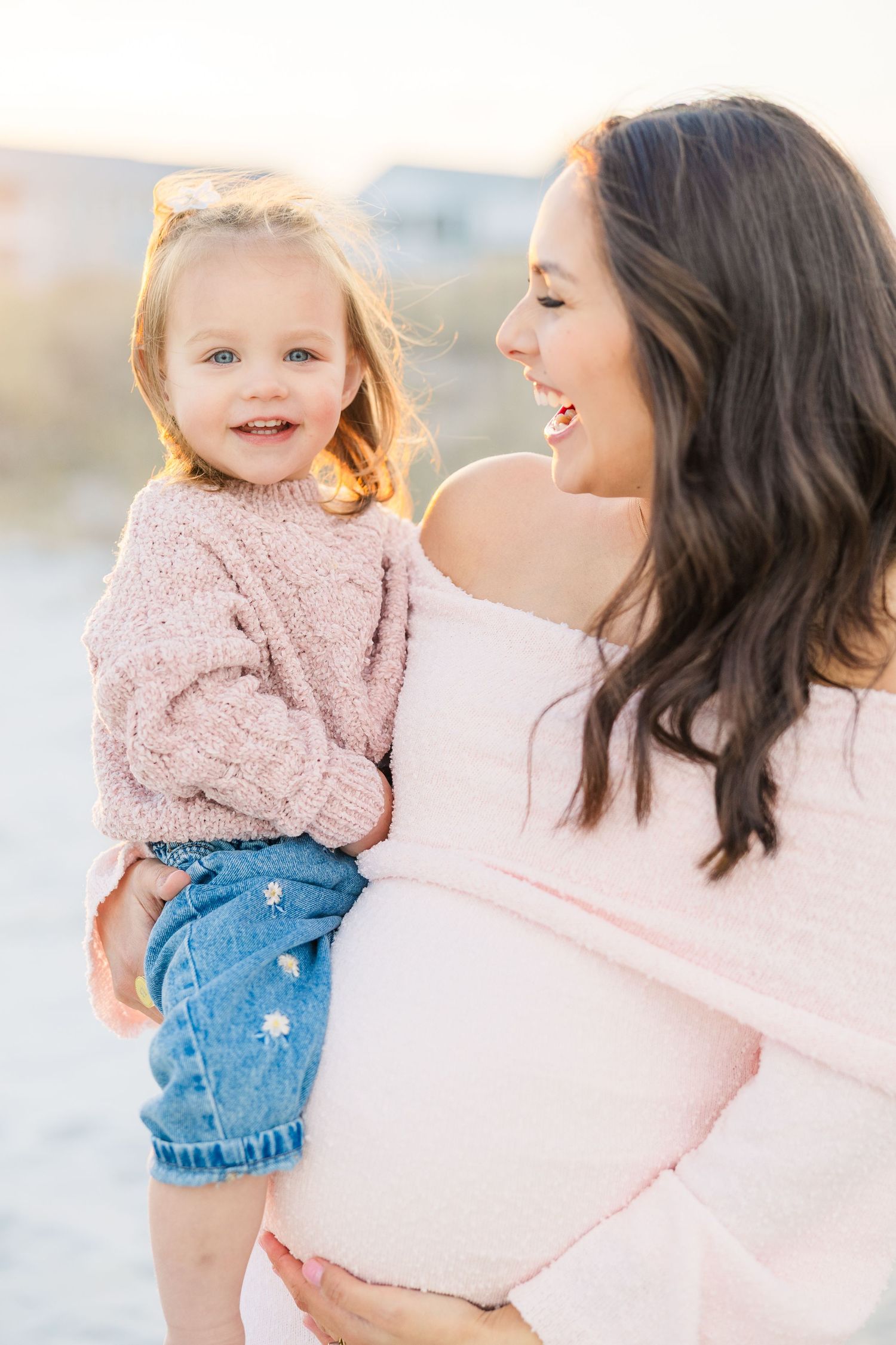 Joyful beach portraits of family wearing coordinated pink and denim outfits.