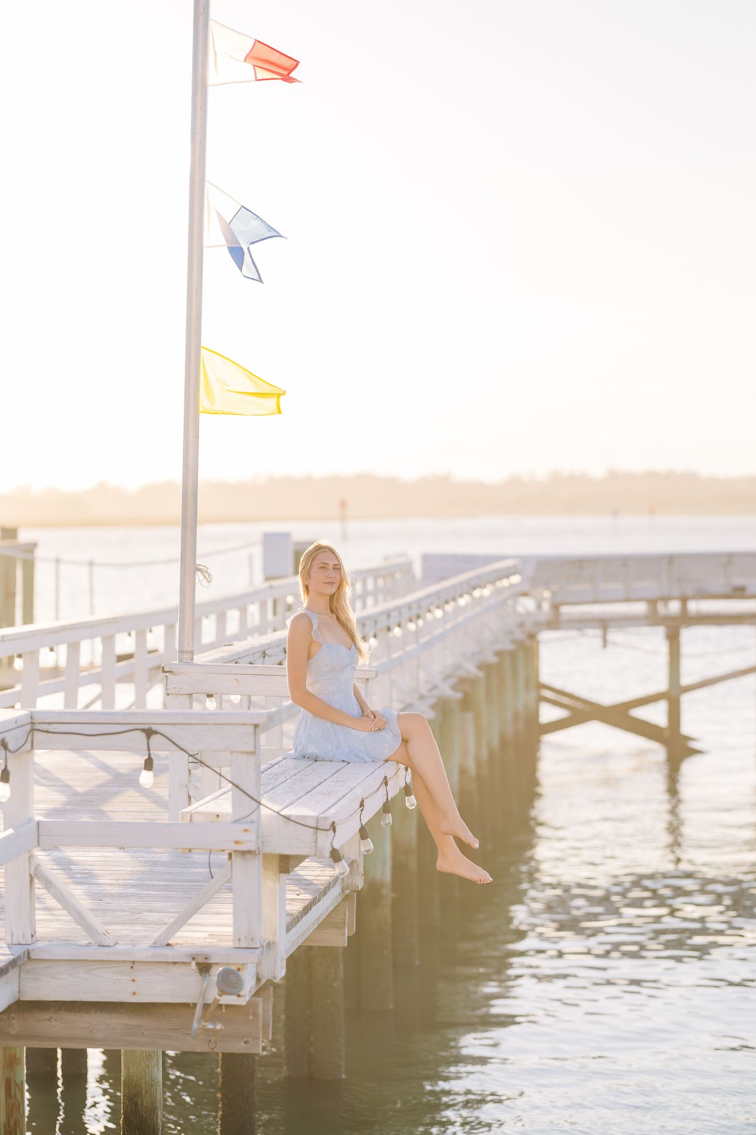 Peaceful waterfront scene with nautical flags and wooden pier at sunset.