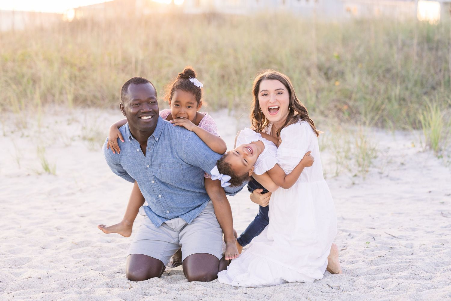 Family sharing a fun moment together while kneeling in the sand.
