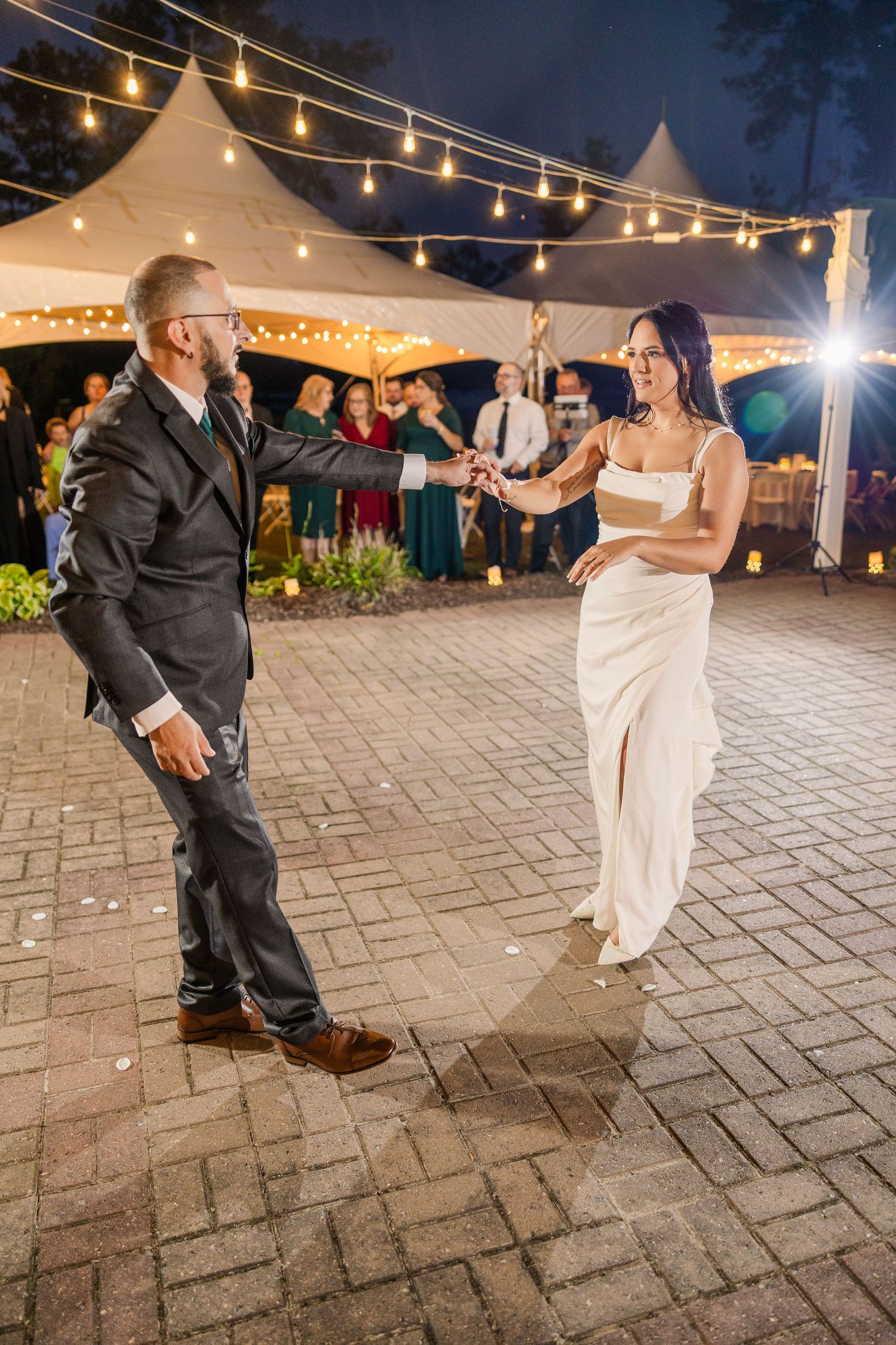 Wedding couple dancing under string lights and tent at outdoor reception wedding groom bride lake Gaston photographer light airy