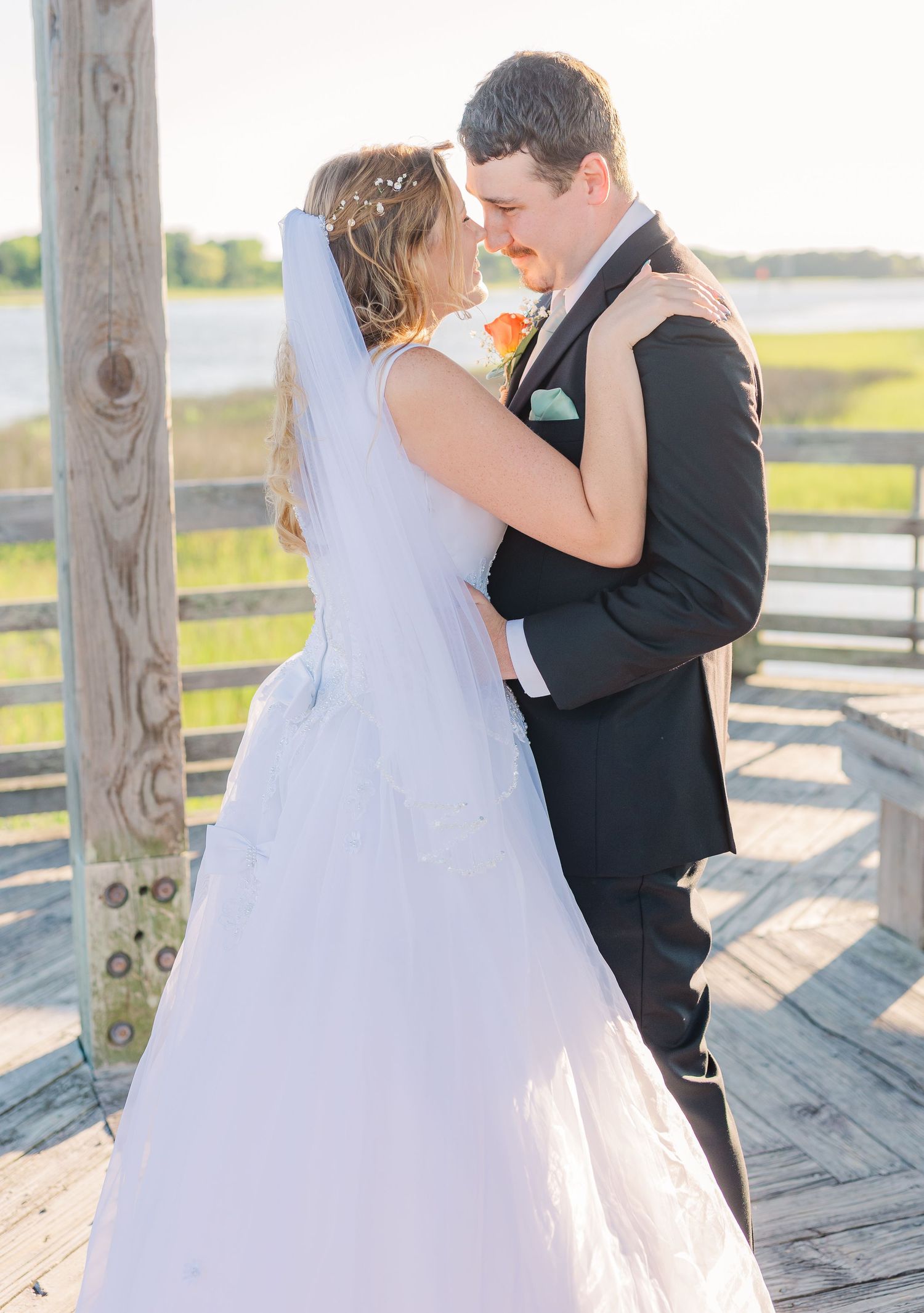 Wedding couple shares intimate dance moves in flowing white dress and black suit on a sunny deck southport elopement wedding bride groom