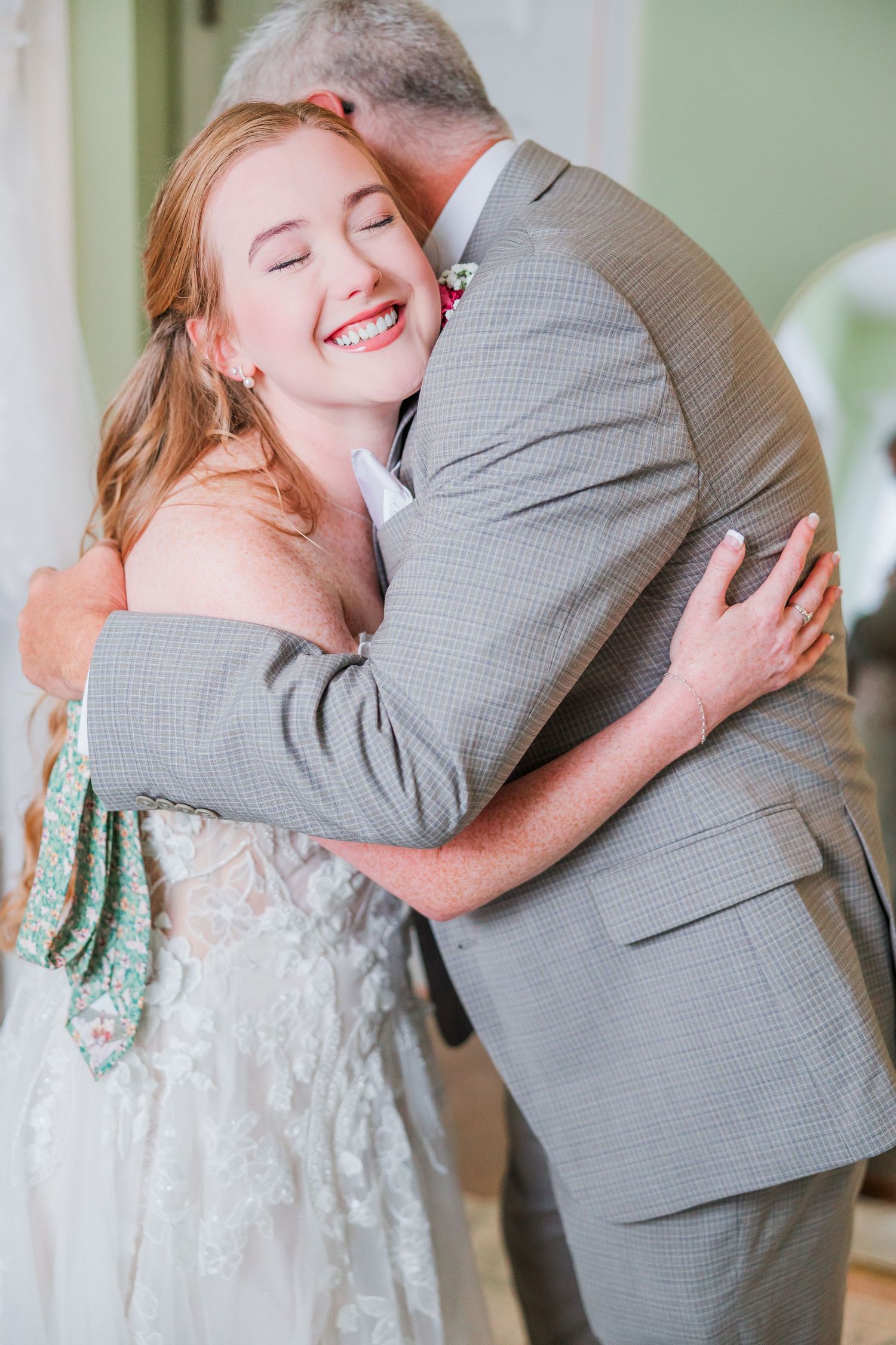 A tender hug shared between two people, with one wearing a white dress and the other in a grey suit in a backyard wedding in wilmington, nc