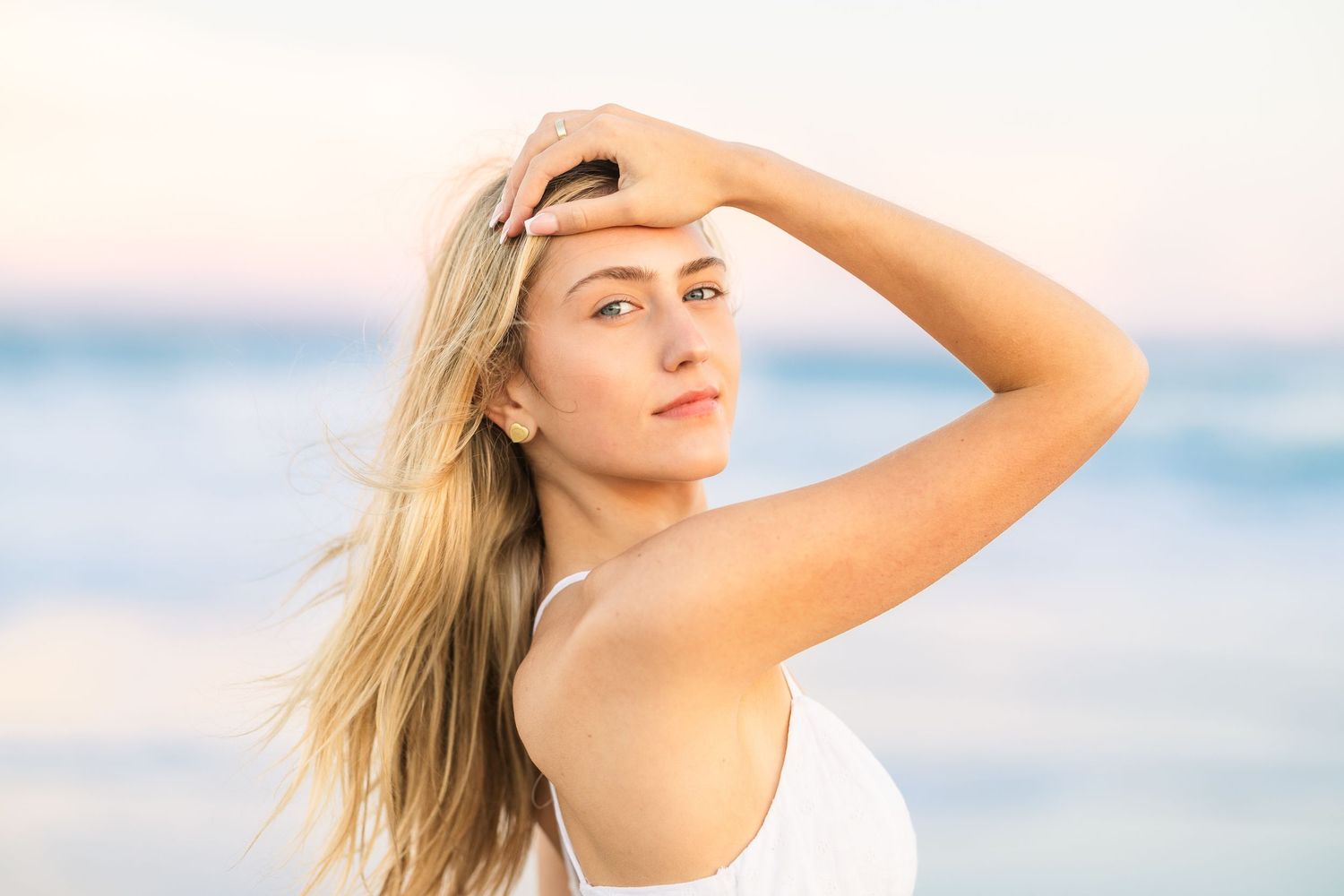 Beachy natural portrait with windswept hair against ocean backdrop.