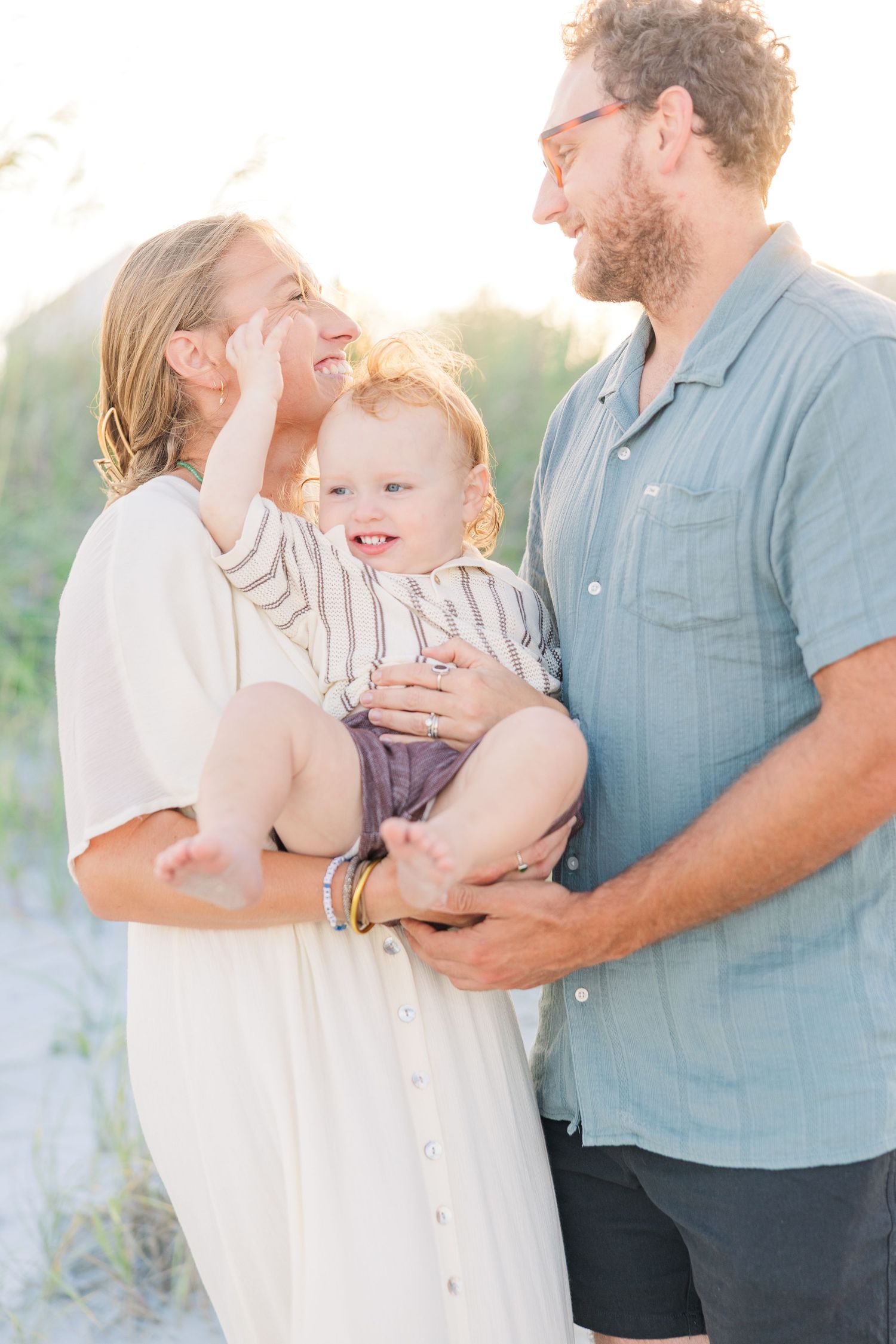 Family shares joyful moment together during sunset beach photoshoot.