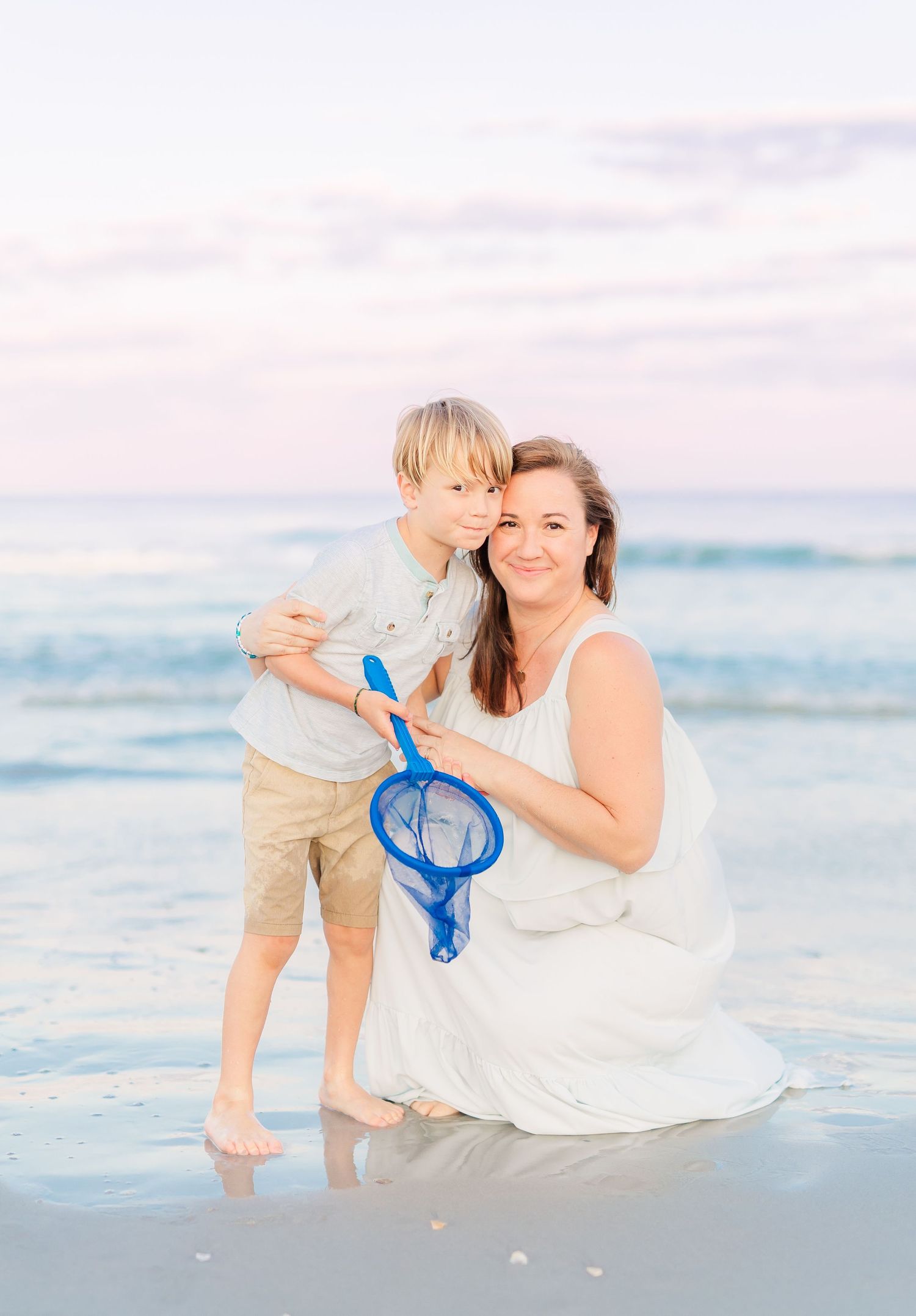 Beach scene with people holding a blue starfish while enjoying the waves.