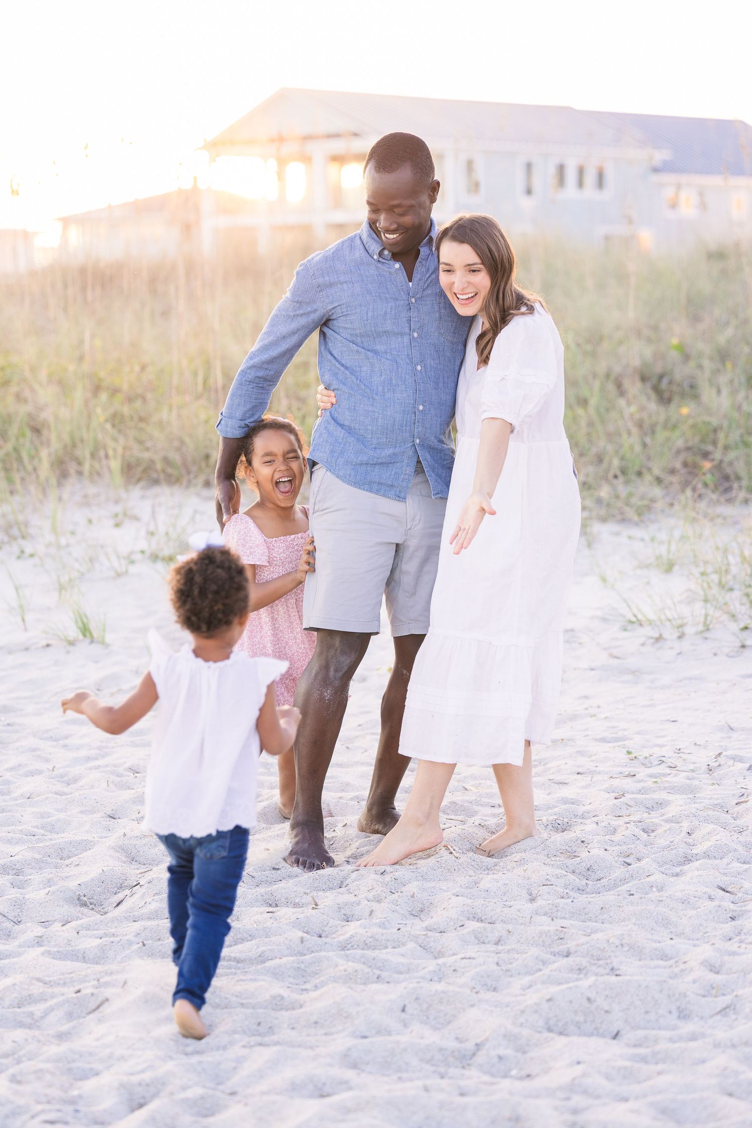 Happy family moment captured on beach with children running in foreground.