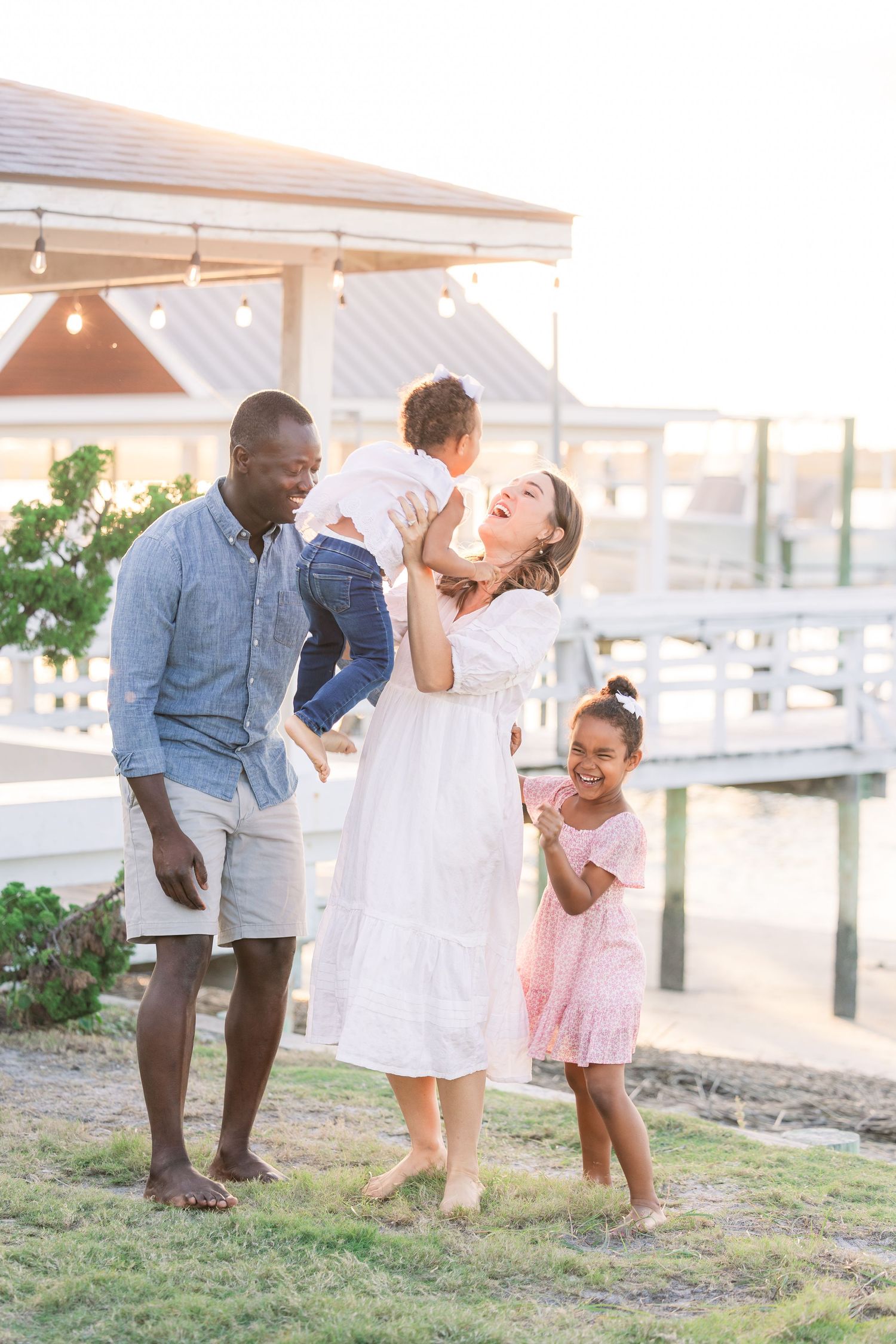 Family sharing laughs and embraces during casual outdoor photoshoot.