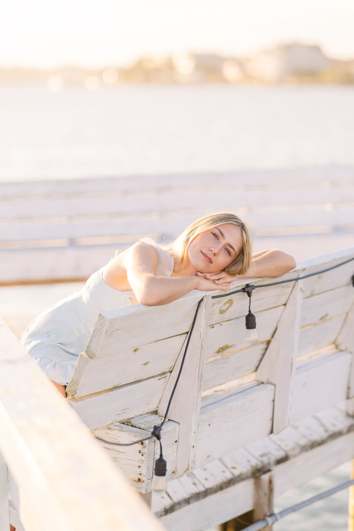 Dreamy beach photography on white wooden benches with soft golden hour lighting.