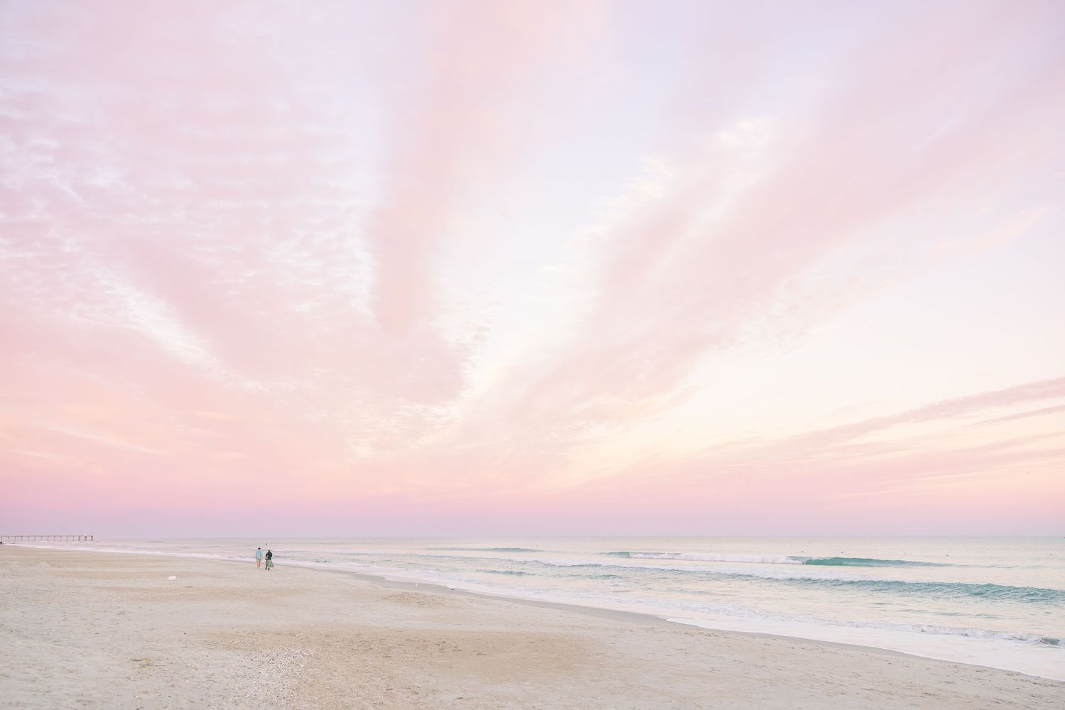 Dreamy pink and purple sunset sky over a peaceful beach landscape.