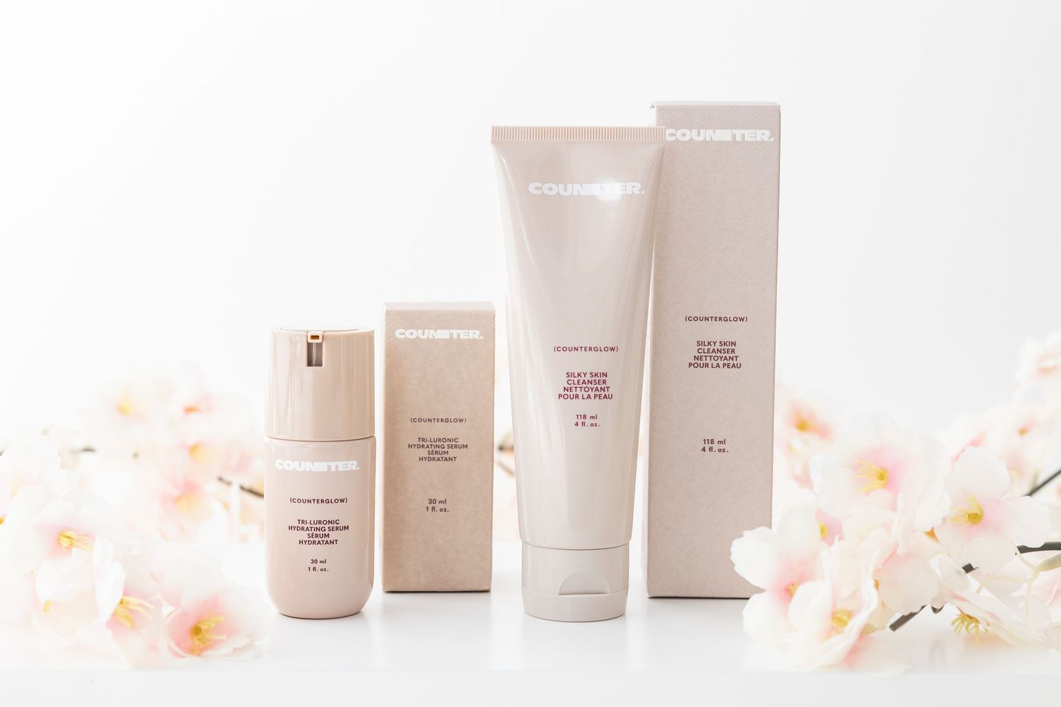 Elegant skincare products display with orchids and neutral packaging against white background.