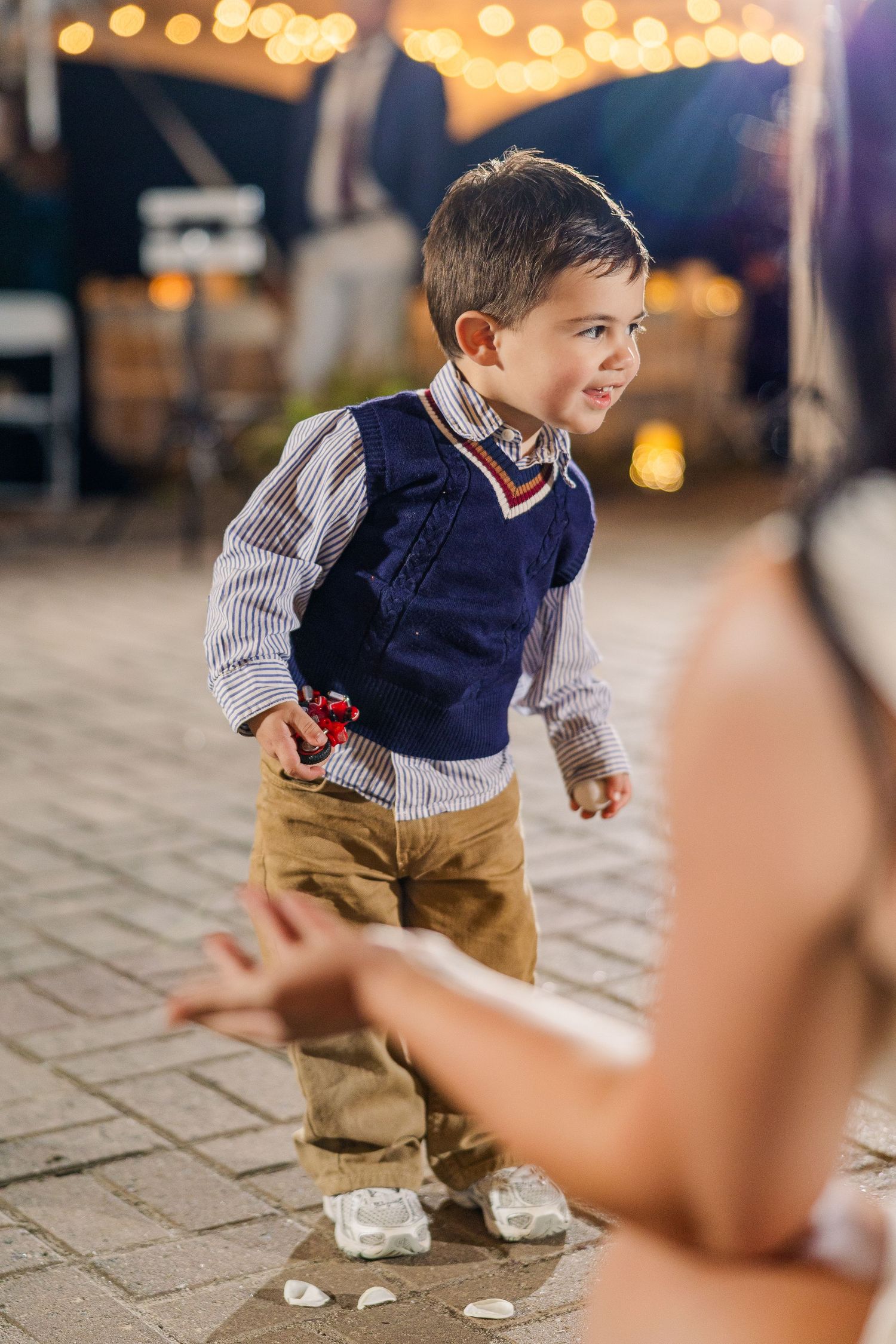 Young child in navy sweater dancing joyfully at outdoor reception wedding groom bride lake Gaston photographer light airy