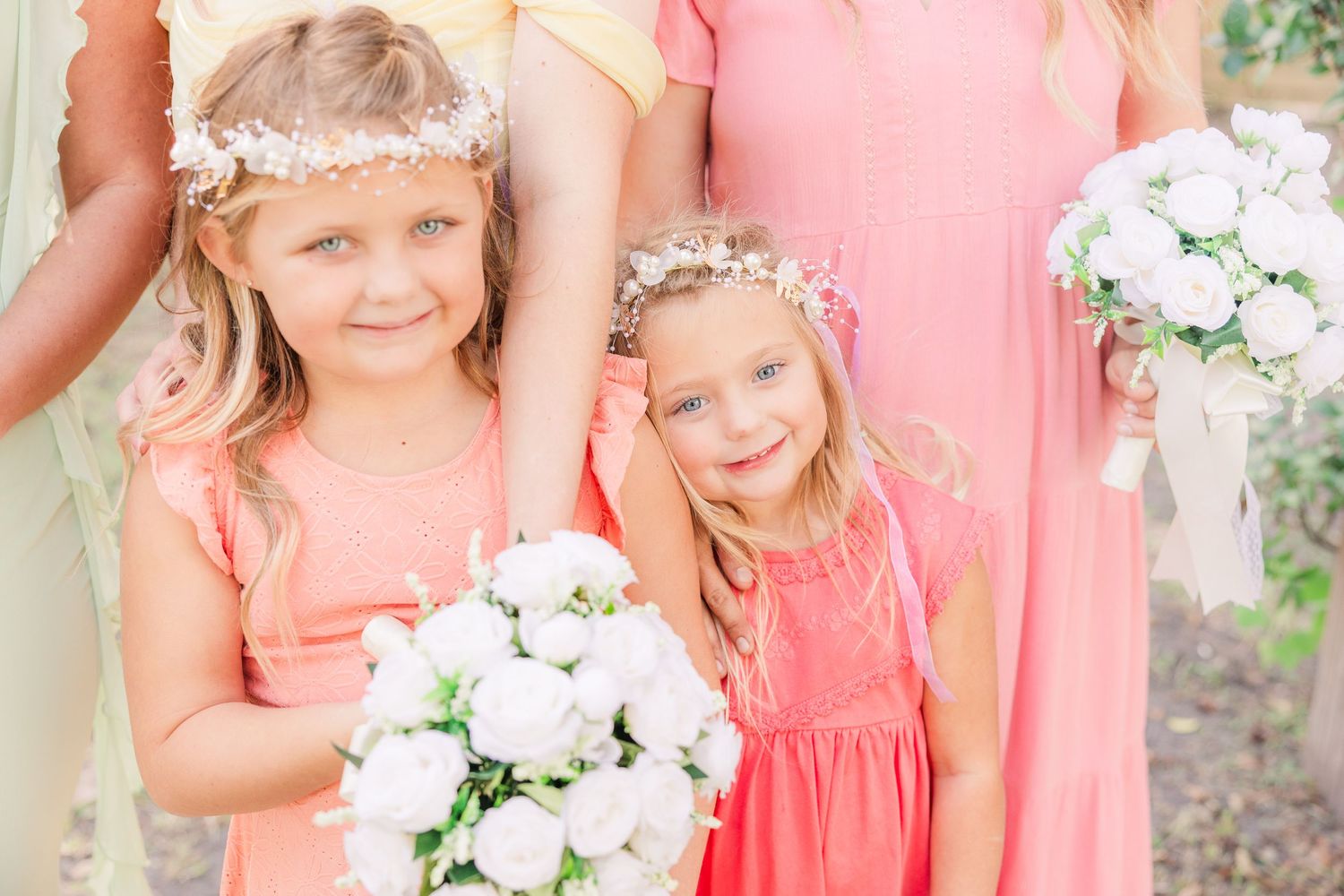 Bridesmaids in coral dresses hold white floral bouquets at an outdoor wedding groom bride wilmington photographer light and airy classic