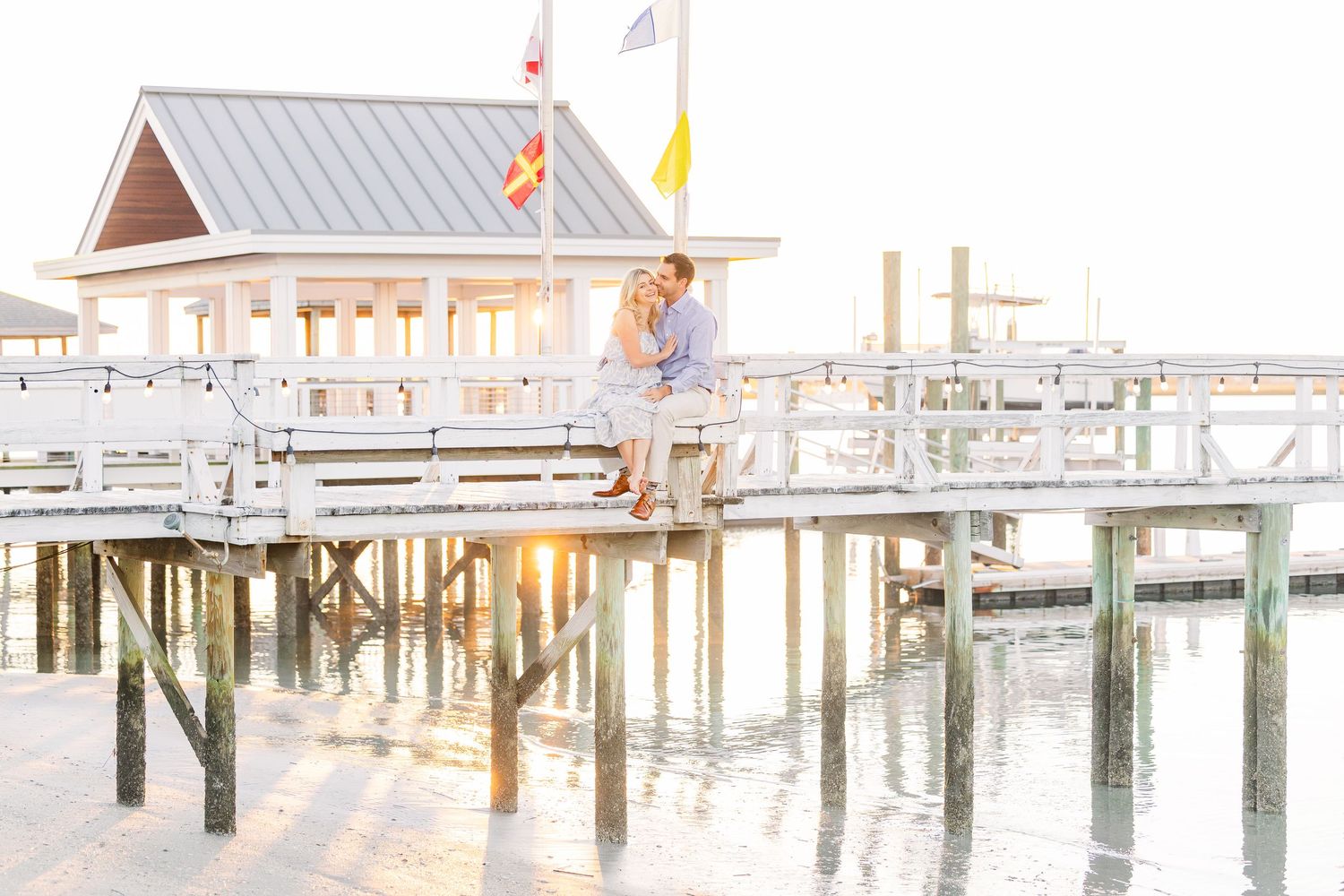 Sunset pier photography with couple sitting against coastal backdrop.
