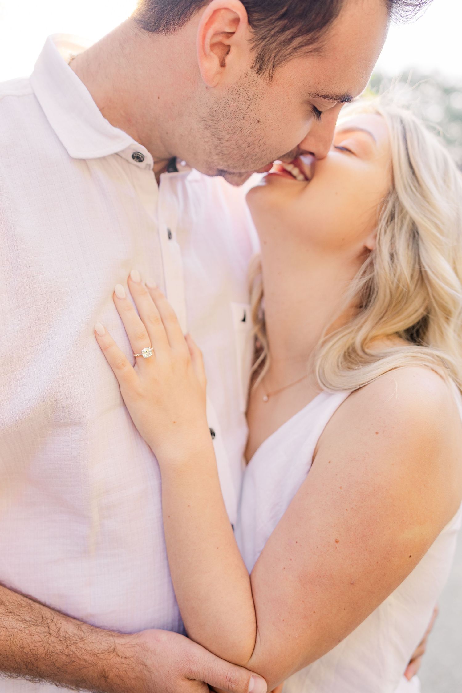 Intimate close-up shots of a couple in white clothing sharing tender moments outdoors.